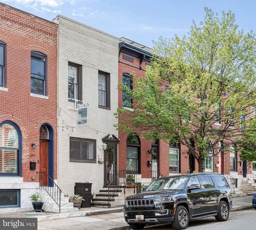 This charming painted brick Highlandtown rowhome with a BRAND NEW ROOF (April 2026) welcomes you with large windows, high ceilings, a vestibule doorway, and charm abound. Inside, hardwood floors, recessed lighting, and crown molding flow through a spacious and wide living room with the authenticity of exposed brick. The updated kitchen shines with stainless steel appliances, a 2025 gas stove, a breakfast bar island with seating, and fresh lighting throughout. A bonus back mudroom with built in cabinetry leads to a private parking pad through a slider door. Upstairs, two large bedrooms await—the front primary bedroom boasts a spacious walk-through closet leading to an en-suite bath with double sinks. The second floor includes a hallway full bath with tub/shower as well as the convenience of upstairs laundry. You could add a deck off the back bedroom easily if you desired. The mostly finished basement offers lots of extra rec room space, as well as storage. A 2020 HVAC and 2020 hot water heater (2026 expansion tank) ensures you can move in without worries - truly turnkey!  Ready to welcome its next owner!