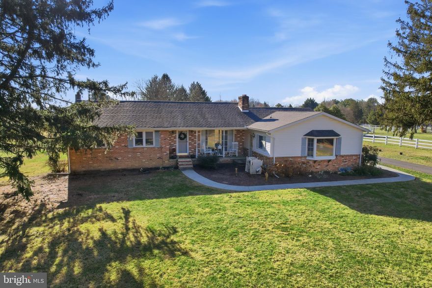 Welcome to 224 Blake Road, a solid and spacious brick ranch set on a picturesque 2.14 acre lot in Fair Hill. Offering 2,396 square feet of living space, this four bedroom, three full bath home includes a thoughtfully designed in-law suite addition, a full basement, and an exceptional outdoor setting with privacy, mature trees, and endless possibilities. Located on a low traffic road with no HOA and no surrounding development, this property delivers space, flexibility, and long term value. Inside, the main living areas are warm and inviting, highlighted by refinished hardwood flooring and abundant natural light. The living room features a large front window, overhead lighting with ceiling fan, a fireplace, and a classic brick accent wall that adds character and charm. The kitchen offers hardwood floors, attractive cabinetry, generous counter space, and both overhead lighting and a ceiling fan. It flows easily into the dining area, creating a functional layout for everyday living and gatherings. The dining room continues the hardwood flooring, features chandelier style lighting, and provides access to the oversized eight foot sliding glass door that opens to the rear deck. The primary bedroom includes hardwood flooring, a large window for natural light, a spacious closet, and a private en suite full bathroom. Additional bedrooms are all well sized with adequate closet space and flexible use options. The hall bath has been fully renovated and showcases beautiful tile flooring, a large updated vanity with mirror, and a tub and shower combination. A convenient mudroom and hallway area adds everyday practicality and helps keep the home organized. Laundry is located in the full, unfinished basement, which also features waterproofing and a “Mama Bear” wood stove, providing additional utility and storage potential. One of the standout features of this property is the one bedroom apartment or in-law suite addition. This private space includes its own entrance, separate utilities, and was updated in 2020 with central air conditioning, new luxury vinyl plank flooring, new tile, and the addition of a walk-in closet. It is ideal for extended family, guests, or potential rental use. Outside, the property truly shines. The expansive lot is surrounded by beautiful pine and maple trees, offering privacy without high maintenance. The yard includes grape vines, a Winesap apple tree, a flowering cherry tree, and a wide variety of established perennials throughout. A rear trex deck creates a peaceful retreat and features a hot tub for relaxing and entertaining. The setting even offers potential for a small farmette for those seeking a more self sufficient lifestyle. Parking and storage are well covered with a detached two plus car garage equipped with electric and water, along with ample driveway parking. The garage and driveway were both updated in 2020, including new garage doors and a new garage roof. This home has seen extensive updates and major system improvements. Recent upgrades include a new washer in 2024, refinished hardwood floors and renovated bathrooms in 2023, new windows and a rear door in 2022, Trex decking, sidewalks, garage roof, garage doors, septic drainfield, and driveway all completed in 2020. During the current ownership, the roof, HVAC system, water heater, plumbing upgrades, basement waterproofing, and water softener have also been completed, offering peace of mind for the next owner. Conveniently located just minutes from restaurants, shopping, major highways, and local destinations such as Fairhill Nature Center and Park, Calvert Recreation Park, and Fairhill Equestrian Center, this home combines privacy, space, and accessibility. This property is also located within the feeder pattern for the #1 ranked Calvert Elementary and other highly rated schools in Cecil county.  A rare opportunity to own a versatile property with room to grow, gather, and enjoy!