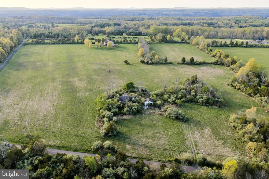 A rare offering of scale and setting, this exceptional 33.8-acre Bucks County estate presents a custom stone residence surrounded by sweeping open fields and wooded borders, creating a private and enduring country retreat. Enrolled in Act 319 and set along a scenic country road, the property offers expansive, level acreage with long pastoral views that are increasingly difficult to replicate.

The 6,200+ square foot residence was thoughtfully constructed with quality materials and craftsmanship, featuring radiant heated floors, Brazilian hardwood flooring, generous room sizes, and a gracious layout designed for both everyday living and entertaining. Well-maintained and comfortably livable as it stands, the home offers the opportunity to further tailor interiors over time to reflect a more personalized aesthetic.

Positioned to one side of the property, the home allows the surrounding acreage to truly shine—offering flexibility for a pool, equestrian pursuits, gardens, or the potential for a guest residence (subject to township approvals). The setting directly borders High Rocks State Park, enhancing both privacy and the natural beauty of the landscape.

Ideally located within easy reach of Doylestown, New Hope, and the area’s renowned farm markets and villages, with convenient access to Philadelphia, Princeton, and New York City, this is a compelling opportunity to secure a property defined by land, lifestyle, and long-term value.