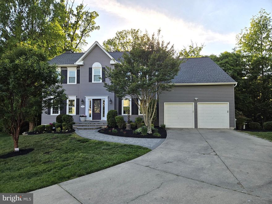 Nestled on more than one-third of an acre and backing to mature trees, this exceptionally well-maintained 5-bedroom, 3½-bath Colonial offers the perfect blend of elegance, comfort, and modern convenience. Stunning landscaping and a custom stone walkway with matching stairs create a beautiful first impression as you approach the home.

Inside, hardwood flooring spans the main and upper levels, complemented by crown molding in select rooms and thoughtful custom touches throughout. Just off the front entry, the private home office features built-in shelving, creating the ideal space for remote work or study.

The expansive kitchen is designed for both everyday living and entertaining, featuring a large center island, abundant cabinetry, a built-in workstation, and impressive smart appliances. Highlights include a WiFi-enabled refrigerator with LED display, deluxe 5-burner gas stove, and dual oven with attachable temperature probe and smart connectivity.

Upstairs, the luxurious primary suite serves as a private retreat with vaulted ceilings, a spacious walk-in closet, and an adjoining sitting room perfect for a home office, reading nook, or hobby space. The newly renovated spa-inspired primary bath showcases a freestanding soaking tub, an elegant custom shower with multiple adjustable body jets, premium Kohler fixtures, shower wand, and precision pressure/temperature controls. A beautifully designed vanity with anti-fog mirror and customizable lighting adds a sophisticated finishing touch.

The additional upper-level bedrooms are generously sized, including an oversized second bedroom with vaulted ceilings and abundant storage. The hall bath has been fully remodeled with stylish modern finishes, and the convenience of an upper-level high-end washer and dryer makes daily living even easier.

The fully finished walkout basement offers exceptional flexibility with complete living accommodations, including an exercise room, additional bedroom or media room, living area, full kitchen, and a newly renovated full bath with its own washer and dryer — ideal for guests, extended family, or multi-generational living.

Outdoor living is equally impressive. Enjoy the newly constructed custom patio, fire pit, mosquito repellent system, hot tub, and spacious deck topped with a gazebo and overhead lighting. The beautifully landscaped yard provides plenty of room for entertaining, relaxing, and enjoying the peaceful wooded backdrop.

This remarkable home combines timeless Colonial charm with luxurious modern upgrades in an exceptional setting.