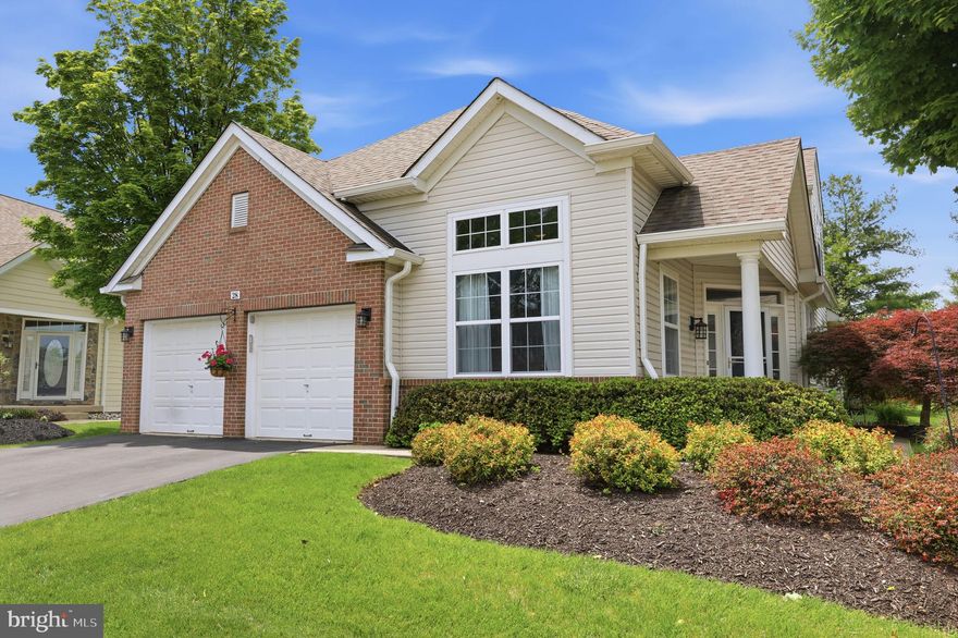 Welcome to 28 Bluebonnet Rd, a beautifully maintained home with stunning curb appeal in the desirable Flowers Mill 55+ Community. Step through the inviting covered front porch and into a grand two-story foyer featuring rich hardwood floors, elegant wainscoting, and a classic oak staircase.  The living room area offers serene sage-green walls, abundant natural light, and a pendant chandelier perfect for everyday meals. The formal dining room impresses with vaulted ceilings, a statement chandelier, and bold slate-blue accent walls. The spacious family room features soaring vaulted ceilings, a white-mantle fireplace with built-in shelving, and a lighted ceiling fan. The well-appointed eat-in kitchen offers rich cherry cabinetry, granite countertops, a full suite of stainless-steel appliances including a gas range, and a center island with additional storage. The sunny breakfast nook with a pendant chandelier offers charming views of the side yard.  The sun-filled Florida room with vaulted ceilings and a sliding glass door, topped with a beautiful arched window, opens directly to the rear patio and sweeping backyard views. The office/den features hardwood floors, sage-green walls, and a lovely garden view.  The spacious primary bedroom retreat features plush carpet, a ceiling fan, and private access to dual closets and a beautifully updated en suite. The luxurious primary en suite boasts a double-sink gray shaker vanity with quartz countertop, dual round mirrors, and a stunning frameless glass shower with sculptural wave tile and hexagon mosaic flooring. The main floor laundry room and charming powder room featuring a pedestal sink and ornate mirror complete this level. Carpeted stairs lead to a versatile upper-level loft that serves as an additional sitting area, perfectly overlooking the dramatic two-story foyer below. The upper level also includes a second bedroom with plush carpet and a ceiling fan,  a second full bath which features a single vanity and tub/shower combo and a generous attic storage closet.  The expansive rear patio is an entertainer's dream with a retractable awning for shade on sunny days, and a gas grill area all overlooking a private, beautifully landscaped backyard. The property backs to a sweeping, park-like common green space with mature trees and rolling lawns offering exceptional privacy. Adding peace of mind year-round, this home also features a whole-house generator. As a resident of the Flowers Mill 55+ community, enjoy amenities including a beautifully appointed clubhouse, indoor and outdoor pools, bocce and pickleball, tennis court, basketball court, walking trails and social events. This community is ideally situated close to restaurants, shops, and travel via Route 1 and I-295.