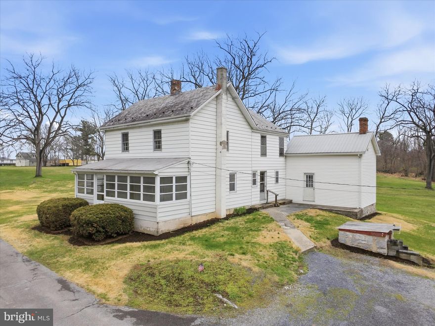 Welcome to 1376 Nolts Rd in Chambersburg, an incredible opportunity for homeownership. Conveniently located just minutes from the amenities of Norland Avenue and Walker Road, yet tucked away at the end of Nolts Road, this property offers privacy and lots of space on 4.29 acres.
With nearly 2,000 square feet of living space, this traditional 3-bedroom, 1.5-bath farmhouse offers character, charm, and versatility. The home features three enclosed porches, providing additional living space to enjoy throughout the year. The main level includes a large country kitchen with new vinyl flooring, and all kitchen appliances convey. The living room and family room feature new carpet, and a flexible office or potential fourth bedroom adds versatility to the main level. A first-floor laundry area and completely renovated half bath provide convenience for the homeowner. Upstairs, you’ll find three generously sized bedrooms with vintage wallpaper and linoleum covering original wood plank flooring, adding to the home’s character. The second level also includes a full bath and a playroom located in the enclosed upper porch. The home is heated by hot water baseboard heat on the main level, while the second floor contains floor registers but does not have an active heat source. The fully floored attic provides storage space or the potential to be finished for additional living area. Outside, the beautiful 4.29-acre setting offers endless possibilities for recreation, gardening, raising animals or simply enjoying your surroundings. The property features numerous mature walnut trees recently valued by a local forester at $16,500. Several outbuildings, including sheds, garages, and workshops, provide storage and ample workspace. Adjacent to the main house is a historic “wash house,” formerly used as a summer kitchen, complete with a closed in fireplace and a second level. A former tenant house also remains on the property, but is currently uninhabitable. The property is serviced by an on-site septic system and private well, with a well pump that is just one year old. The home also features updated 100-amp electrical service. With its acreage, character, and multiple outbuildings, this property offers a rare opportunity to create the country homestead you’ve always envisioned. Bring your ideas and make it your own.