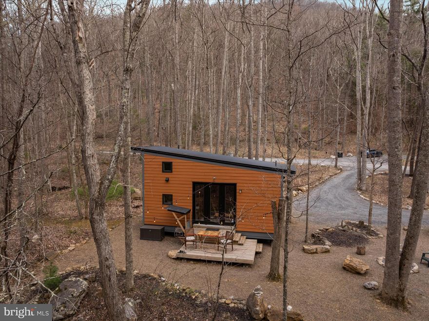 “Creekside” feels like a quiet secret whispered through the trees—where the rhythm of a year-round mountain stream becomes part of everyday life. Set gently on 2.55 wooded acres and just 50 feet from the water’s edge, this thoughtfully designed 374-square-foot tiny cabin with loft offers a rare blend of simplicity, intention, and proven success. For over five years, Creekside has welcomed guests as a highly rated and fully operational Airbnb, earning glowing reviews and a loyal following. Inside, the space unfolds with surprising ease—an open, airy feel anchored by warm textures and smart design. The cabin comfortably sleeps four, with a queen bed on the main level and two twin beds tucked into the loft above. The kitchen is both modern and efficient, outfitted with a two-burner gas stove, under-counter refrigerator, microwave, Keurig coffee maker, toaster, and all the essentials to make a stay feel effortless. A cozy living area invites slow mornings and quiet evenings, complete with rocking chairs, a dining or work table, ceiling fan, and wall-mounted flat-screen TV. Thoughtful upgrades like tankless hot water and fiber-optic internet (up to 95 Mbps) ensure comfort without compromise. Offered fully furnished, Creekside is truly turnkey—including linens making it ready for its next chapter from day one. Beyond the cabin itself, the opportunity expands. The property carries county approval for two additional one-bedroom tiny cabins, with plans included—inviting a vision of growth, income, or a thoughtfully curated retreat experience. This is more than a property—it’s a place to pause, to invest, to imagine what comes next. Come walk the land, listen to the water, and experience all that 949 Dumpling Run Road quietly offers. 
Airbnb listing: https://www.airbnb.com/rooms/45966594?viralityEntryPoint=1&unique_share_id=8CDE06B5-D554-45B5-A1D2-3997B08A2443&slcid=2fd64da927534288b77b264986a30ba2&s=76&feature=share&adults=1&channel=na