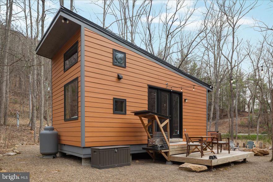 “Creekside” feels like a quiet secret whispered through the trees—where the rhythm of a year-round mountain stream becomes part of everyday life. Set gently on 2.55 wooded acres and just 50 feet from the water’s edge, this thoughtfully designed 374-square-foot tiny cabin with loft offers a rare blend of simplicity, intention, and proven success. For over five years, Creekside has welcomed guests as a highly rated and fully operational Airbnb, earning glowing reviews and a loyal following. Inside, the space unfolds with surprising ease—an open, airy feel anchored by warm textures and smart design. The cabin comfortably sleeps four, with a queen bed on the main level and two twin beds tucked into the loft above. The kitchen is both modern and efficient, outfitted with a two-burner gas stove, under-counter refrigerator, microwave, Keurig coffee maker, toaster, and all the essentials to make a stay feel effortless. A cozy living area invites slow mornings and quiet evenings, complete with rocking chairs, a dining or work table, ceiling fan, and wall-mounted flat-screen TV. Thoughtful upgrades like tankless hot water and fiber-optic internet (up to 95 Mbps) ensure comfort without compromise. Offered fully furnished, Creekside is truly turnkey—including linens making it ready for its next chapter from day one. Beyond the cabin itself, the opportunity expands. The property carries county approval for two additional one-bedroom tiny cabins, with plans included—inviting a vision of growth, income, or a thoughtfully curated retreat experience. This is more than a property—it’s a place to pause, to invest, to imagine what comes next. Come walk the land, listen to the water, and experience all that 949 Dumpling Run Road quietly offers. 
Airbnb listing: https://www.airbnb.com/rooms/45966594?viralityEntryPoint=1&unique_share_id=8CDE06B5-D554-45B5-A1D2-3997B08A2443&slcid=2fd64da927534288b77b264986a30ba2&s=76&feature=share&adults=1&channel=na