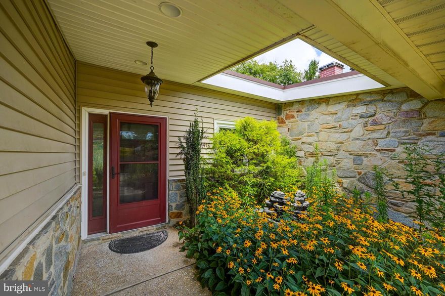 Idyllically sited on a corner lot in Stevenson, curb appeal abounds in this impeccably maintained three-bedroom, two-bathroom home with over 2,500 finished square feet of living space. This updated property features a welcoming foyer that flows seamlessly into the expansive living room and family room which are separated by a stacked stone wood burning fireplace. The formal dining room is located just off the spacious renovated kitchen which provides an abundance of high-end mid-century modern style cabinetry and granite counters, an oversized tiered island with plenty of seating, a double wall oven, four burner solid surface  Induction cooktop, and a side by side refrigerator. Adding to the special appeal of the kitchen is the expanded breakfast nook with butler pantry, slider to the private side patio, upgraded tile floors, and recessed lighting. The entertaining options continue with the light-filled three-season sunroom located just off the family room. The private bedroom wing of the property presents a primary suite with hardwood floors, fresh paint, and two closets with custom-designed closet systems. The primary bathroom offers a double bowl vanity with granite counters, tile floors and wall surround, and a shower with designer tile and seamless glass surround. Other features include upgraded lighting and plumbing fixtures. There are two additional bedrooms, an updated hall bathroom with double bowl vanity, a laundry room with front loading washer and dryer, utility sink, and a storage room off the carport on this level. The showstopper in this property is the mature self-pollinating lush landscaping and stamped concrete patio overlooking the rear yard with beautiful views of the surrounding nature. Other notable features include a white granular rubber roof and replaced gutters (2016), replaced siding with a second layer of insulation (2010), replaced energy-efficient doors and windows (2010), fully replaced electric panel (2009), new furnace (2021), Rhinnai tankless water heater, wood floors in the dining room and bedroom wing, updated lighting and plumbing fixtures throughout, an oversized circular driveway with carport, and so much more! This desirable residence is near the Falls Road corridor, The Quarry Shops, and Interstates 695 and 83. Delights await as you explore this property.