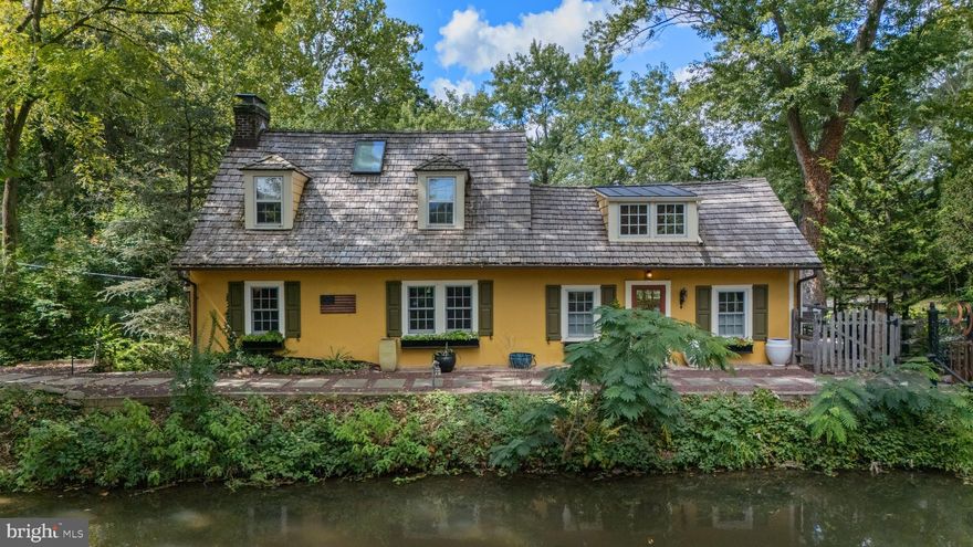Welcome to the iconic and enchanting Pumpkin Seed Cottage.
Nestled along the picturesque Delaware Canal, this magical property offers a serene and captivating setting. Steeped in history, this charming 1800s cottage was once the home of renowned impressionist painter Mary Elizabeth Price, who named the property Pumpkin Seed during her residence from the 1920s through the mid-1960s.
The home is a perfect blend of old-world charm and modern-day amenities, thoughtfully updated with exceptional craftsmanship. Original details such as exposed beams, hardwood floors, two fireplaces, and custom built-ins create a warm and inviting atmosphere.
The sun-drenched, gourmet eat-in kitchen is a standout feature, boasting vaulted ceilings, a center island with a built-in wine refrigerator and custom stone countertop, a farmhouse sink, stainless steel appliances, a Wolf oven and gas range with vented hood, custom cabinetry with built-in pantry, and a cozy gas fireplace. French doors open to a wraparound deck complete with a built-in grill, granite countertops, and a hot tub.  From the deck, follow a pathway to a European-inspired stone patio — a perfect spot to gather around the firepit and enjoy a crisp fall evening. The outdoor spaces are ideal for entertaining or relaxing. The grounds also feature an enclosed vegetable garden, a firewood storage shed, and a spacious storage area beneath the deck.
The main level includes a stunning great room with a stone wood-burning fireplace, exposed beams, hardwood floors, and built-ins, as well as a stylish powder room for guests. There are three en-suite bedrooms, one on each level, offering privacy and flexibility.
The main-level primary suite is a peaceful retreat, featuring a cathedral ceiling with exposed beams, a wood-paneled accent wall, a walk-in closet with built-ins, additional closets and storage, and a luxurious bathroom with a marble vanity and tiled, glass-enclosed shower.
Upstairs, a second en-suite bedroom offers a cathedral ceiling, charming window seats, and a custom wood door that opens to a balcony overlooking the kitchen. A sliding barn door provides access to the private, updated bathroom.
The walkout lower level features the third en-suite bedroom (currently used as an office and den) with a large picture window showcasing bucolic views. This level also includes an updated full bathroom, laundry room, and mechanical room with updated systems. Additional features include a whole-house generator and a newer cedar shake roof with copper gutters.
Enjoy direct access to the Delaware Canal for kayaking, canoeing, and fishing, or take a stroll or bike ride along the scenic towpath. Just a short walk to the vibrant towns of New Hope and Lambertville, you’ll find boutiques, restaurants, festivals, and live performances at the Bucks County Playhouse.  Conveniently located near Routes 202 and 263 with an easy commute into New Jersey.
Whether you’re seeking a serene waterfront retreat or a distinctive full-time residence, Pumpkin Seed Cottage offers a rare blend of history, charm, and modern comfort.