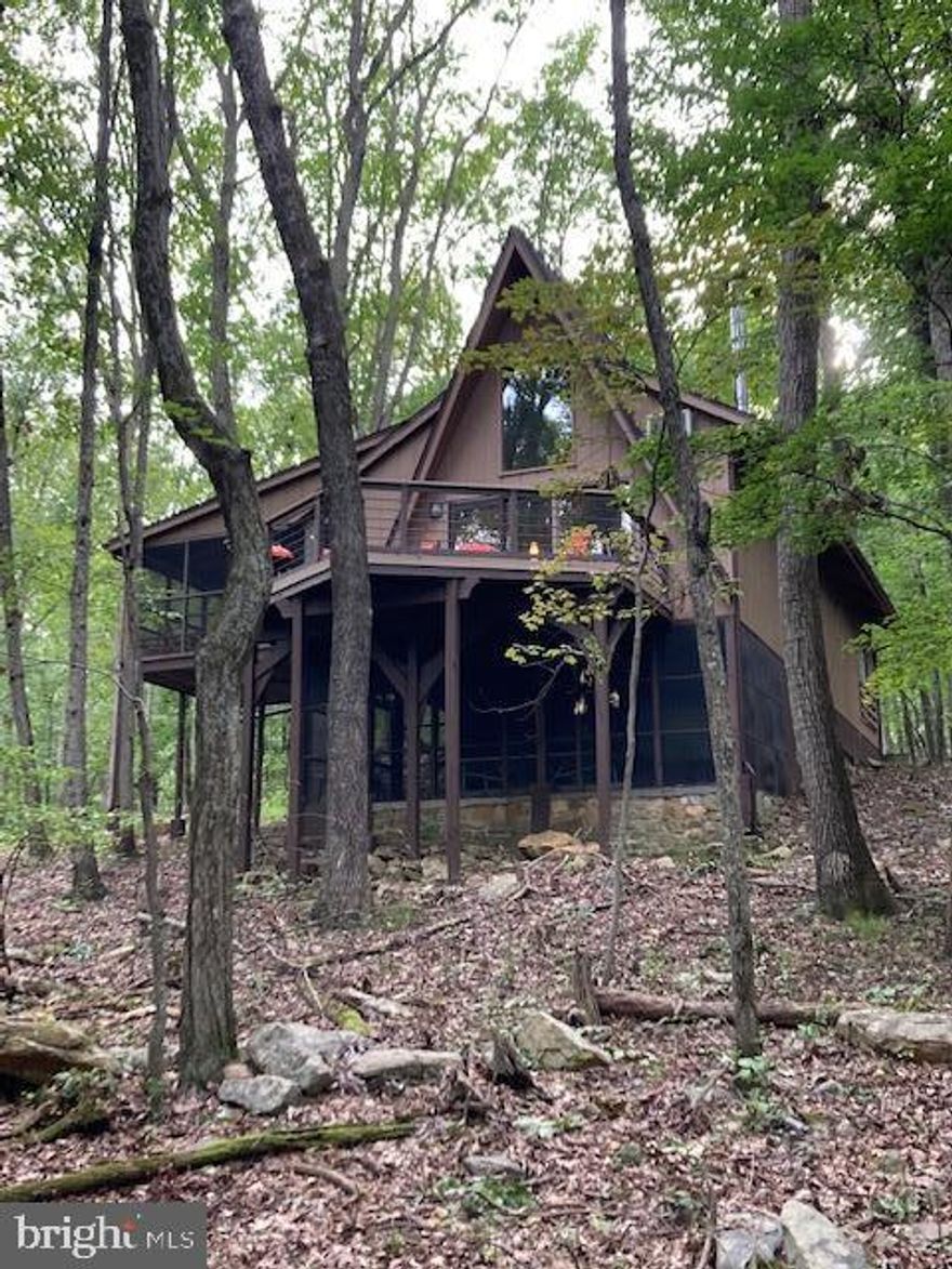 Looking for the perfect getaway from the hustle and bustle of the city? This A-frame style chalet is nestled in the trees of Coolfont Mountainside, just minutes from historic Berkeley Springs.  Features 3 BR, 3.5 baths,  open floor plan with spacious great room, wood burning stove , main level master bedroom, and a screened in porch. Upstairs is a cozy loft bedroom. The finished lower level has large family room, bedroom, full bath and a screened in patio.  Enjoy the community pool and tennis courts. Won't last long!