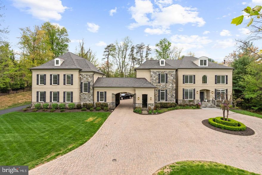 Gracefully positioned at the end of a private cul-de-sac on 2.12 manicured acres, this exceptional French Country estate with a private guest house and resort-style pool offers timeless elegance along the coveted Great Falls–McLean border within the Langley High School pyramid. Built by Keswick Homes, the residence spans 13,448 square feet and showcases soaring ceilings, Brazilian cherry hardwood floors, exquisite millwork, expansive windows, and a three-level elevator. A long private drive leads to a motor court and porte-cochère, setting the tone for the home’s impressive scale and craftsmanship. The chef’s kitchen is beautifully appointed with Sub-Zero, Wolf, and Miele appliances, dual islands, custom cabinetry, and seamless flow to the breakfast room and grand great room with a fireplace. Formal living and dining rooms and light-filled gathering spaces create the perfect balance of luxury and livability. The upper-level primary suite offers a private sitting room, fireplace, balcony, dual custom walk-in closets, and a spa-inspired bath. Rounding out the five en suite bedrooms on this level are a primary-size suite and an independent wing of three generously proportioned bedrooms, one with a zero-entry shower with bench seating, extra-wide doorways, and wide hallway access to the elevator, ideal for multigenerational living. The expansive lower level features a media room, wet bar, billiards, recreation spaces, flex rooms, and guest accommodations. Outdoor living is truly spectacular with a 20x40 heated saltwater pool, retractable cover, outdoor kitchen with Viking appliances, stone fireplace pavilion, and over 6,000 square feet of Pennsylvania bluestone patios and covered porches. A detached 3,000+ square-foot carriage house includes its own kitchen, family room, two bedrooms, and a commercial-grade gym, creating an ideal guest residence, wellness retreat, or multigenerational living environment. Moments from Tysons, McLean, and Washington, this extraordinary estate offers privacy, scale, and resort-style luxury in one of the region’s most prestigious settings.