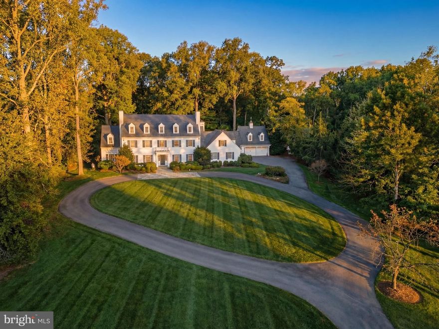 Tucked away behind the nationally renowned Congressional Country Club, its namesake Country Club Drive is one of Bethesda’s most prestigious streets, with just 26 estate homes set along sweeping, picturesque curves. Set far back from the street on a verdant two-acre lot, this quintessential custom-built residence was originally constructed for its discerning owner.
Approached by an elegant circular driveway, the white brick and siding façade, capped by a synthetic slate roof, evokes classic New England colonial architecture and an enduring sense of quiet luxury. A portico entry and mahogany front door framed by transom windows open to a gracious foyer with a grand staircase.
Formal living and dining rooms flank the reception hall in a traditional center hall layout. Each is generously scaled for entertaining and features one of the home’s six fireplaces. The dining room includes built-in china displays, while the living room flows into a richly paneled library with its own fireplace, connecting seamlessly to the family room. Bathed in natural light from double French doors, the family room features a coffered ceiling and stone fireplace, adding warmth and intimacy.
At the heart of the home is a chef’s kitchen, reimagined by Jack Rosen Custom Kitchens to blend beauty and function. White shaker cabinetry contrasts with dark hardwood floors, while a honed Carrara marble island pairs elegantly with leathered granite perimeter counters. A custom stainless-steel hood anchors the space, complemented by a full suite of Wolf and SubZero appliances. The butler’s pantry features glass-front cabinetry and a wine fridge, linking to the dining room. A sunlit breakfast room with cathedral ceiling and an adjoining keeping room bring the outdoors in. A mudroom and full bath complete the main level.
The upper level features a private primary suite wing with a covered terrace, sitting room, and breakfast bar tucked behind French doors. The spa-like bath includes a soaking tub, and the dressing room offers extensive custom built-ins. Four additional bedrooms and three baths complete this level, while a top-level loft provides flexible space.
The lower level is designed for entertaining, with a recreation room featuring a wet bar and screening area, along with a fireplace-adorned office, fitness center, bedroom, and full bath.
Resort-style grounds include a screened porch opening to a flagstone patio with fire pit and grilling station, a heated pool with automatic cover, and a two-level guest house. Expansive lawns, mature trees, and curated landscaping create a private retreat.
Proximate to top-rated public and private schools, lush parks, and scenic byways the residence offers an unmatched combination of elegance, comfort, and livability in a setting that feels worlds away yet is moments from the heart of Bethesda. Impeccably designed, meticulously updated, and beautifully sited, 8509 Country Club Drive represents one of Bethesda’s finest offerings in an extraordinary home exemplifying timeless luxury.