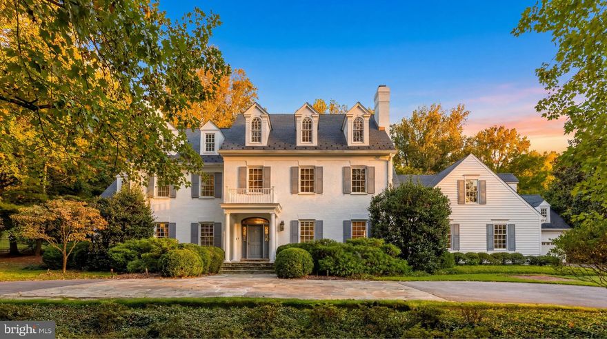 Tucked away behind the nationally renowned Congressional Country Club, its namesake Country Club Drive is one of Bethesda’s most prestigious streets, with just 26 estate homes set along sweeping, picturesque curves. Set far back from the street on a verdant two-acre lot, this quintessential custom-built residence was originally constructed for its discerning owner.
Approached by an elegant circular driveway, the white brick and siding façade, capped by a synthetic slate roof, evokes classic New England colonial architecture and an enduring sense of quiet luxury. A portico entry and mahogany front door framed by transom windows open to a gracious foyer with a grand staircase.
Formal living and dining rooms flank the reception hall in a traditional center hall layout. Each is generously scaled for entertaining and features one of the home’s six fireplaces. The dining room includes built-in china displays, while the living room flows into a richly paneled library with its own fireplace, connecting seamlessly to the family room. Bathed in natural light from double French doors, the family room features a coffered ceiling and stone fireplace, adding warmth and intimacy.
At the heart of the home is a chef’s kitchen, reimagined by Jack Rosen Custom Kitchens to blend beauty and function. White shaker cabinetry contrasts with dark hardwood floors, while a honed Carrara marble island pairs elegantly with leathered granite perimeter counters. A custom stainless-steel hood anchors the space, complemented by a full suite of Wolf and SubZero appliances. The butler’s pantry features glass-front cabinetry and a wine fridge, linking to the dining room. A sunlit breakfast room with cathedral ceiling and an adjoining keeping room bring the outdoors in. A mudroom and full bath complete the main level.
The upper level features a private primary suite wing with a covered terrace, sitting room, and breakfast bar tucked behind French doors. The spa-like bath includes a soaking tub, and the dressing room offers extensive custom built-ins. Four additional bedrooms and three baths complete this level, while a top-level loft provides flexible space.
The lower level is designed for entertaining, with a recreation room featuring a wet bar and screening area, along with a fireplace-adorned office, fitness center, bedroom, and full bath.
Resort-style grounds include a screened porch opening to a flagstone patio with fire pit and grilling station, a heated pool with automatic cover, and a two-level guest house. Expansive lawns, mature trees, and curated landscaping create a private retreat.
Proximate to top-rated public and private schools, lush parks, and scenic byways the residence offers an unmatched combination of elegance, comfort, and livability in a setting that feels worlds away yet is moments from the heart of Bethesda. Impeccably designed, meticulously updated, and beautifully sited, 8509 Country Club Drive represents one of Bethesda’s finest offerings in an extraordinary home exemplifying timeless luxury.