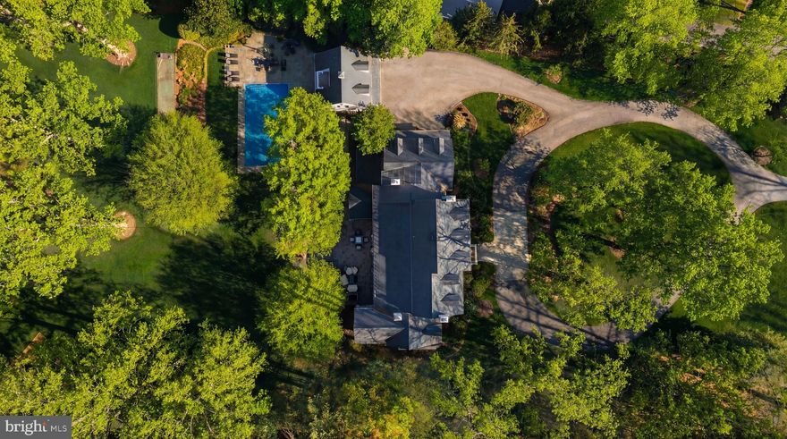 Tucked away behind the nationally renowned Congressional Country Club, its namesake Country Club Drive is one of Bethesda’s most prestigious streets, with just 26 estate homes set along sweeping, picturesque curves. Set far back from the street on a verdant two-acre lot, this quintessential custom-built residence was originally constructed for its discerning owner.
Approached by an elegant circular driveway, the white brick and siding façade, capped by a synthetic slate roof, evokes classic New England colonial architecture and an enduring sense of quiet luxury. A portico entry and mahogany front door framed by transom windows open to a gracious foyer with a grand staircase.
Formal living and dining rooms flank the reception hall in a traditional center hall layout. Each is generously scaled for entertaining and features one of the home’s six fireplaces. The dining room includes built-in china displays, while the living room flows into a richly paneled library with its own fireplace, connecting seamlessly to the family room. Bathed in natural light from double French doors, the family room features a coffered ceiling and stone fireplace, adding warmth and intimacy.
At the heart of the home is a chef’s kitchen, reimagined by Jack Rosen Custom Kitchens to blend beauty and function. White shaker cabinetry contrasts with dark hardwood floors, while a honed Carrara marble island pairs elegantly with leathered granite perimeter counters. A custom stainless-steel hood anchors the space, complemented by a full suite of Wolf and SubZero appliances. The butler’s pantry features glass-front cabinetry and a wine fridge, linking to the dining room. A sunlit breakfast room with cathedral ceiling and an adjoining keeping room bring the outdoors in. A mudroom and full bath complete the main level.
The upper level features a private primary suite wing with a covered terrace, sitting room, and breakfast bar tucked behind French doors. The spa-like bath includes a soaking tub, and the dressing room offers extensive custom built-ins. Four additional bedrooms and three baths complete this level, while a top-level loft provides flexible space.
The lower level is designed for entertaining, with a recreation room featuring a wet bar and screening area, along with a fireplace-adorned office, fitness center, bedroom, and full bath.
Resort-style grounds include a screened porch opening to a flagstone patio with fire pit and grilling station, a heated pool with automatic cover, and a two-level guest house. Expansive lawns, mature trees, and curated landscaping create a private retreat.
Proximate to top-rated public and private schools, lush parks, and scenic byways the residence offers an unmatched combination of elegance, comfort, and livability in a setting that feels worlds away yet is moments from the heart of Bethesda. Impeccably designed, meticulously updated, and beautifully sited, 8509 Country Club Drive represents one of Bethesda’s finest offerings in an extraordinary home exemplifying timeless luxury.