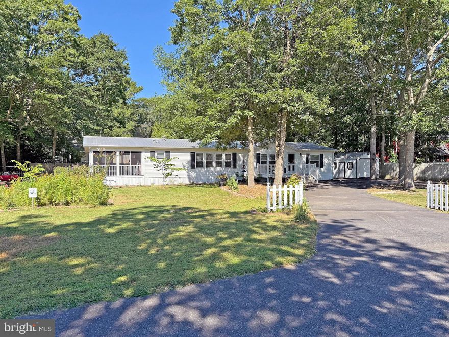 Every day can be a beach day when you live in Shady Dell Park! Spacious 1,792 sq. ft. doublewide manufactured home is on a 1/4-acre lot located less than 3 miles from Bethany’s boardwalk and beach. And this home is just 8 miles from the Fenwick Island State Park beach. The living room features vaulted ceilings, a wood-burning fireplace, and it adjoins the dining area. Big eat-in kitchen with a breakfast-bar island. The kitchen has luxury quartz countertops and a white appliance package including a gas range, range hood, refrigerator, and a dishwasher. The laundry room has a side-by-side washer & dryer set, as well as table space to fold your clothes or a place for a little home office. The utility closet houses the newer tankless water heater and the water filtration system. Popular split bedroom plan. Main bedroom is en Suite with an updated bath including a newer double-sink vanity and a large step-in shower. The other two bedroom share the second full bath in the hall; that bath was also updated. You are going to love the expansive screened porch. There’s also a patio area overlooking the stunning pollinator garden. Privacy fencing in the backyard. The storage shed has electric including a dedicated 30amp RV outlet, too. Circular/U-shaped driveway with extra parking spaces for your RV, boat, and other vehicles. So many upgrades between 2018 - 2025 including a new metal roof on the home and shed. Front porch has been upgraded with composite decking materials for easy care. Public sewer & a private well (60'). Low HOA dues of just $75/year and not too many rules. Golf carts are allowed.