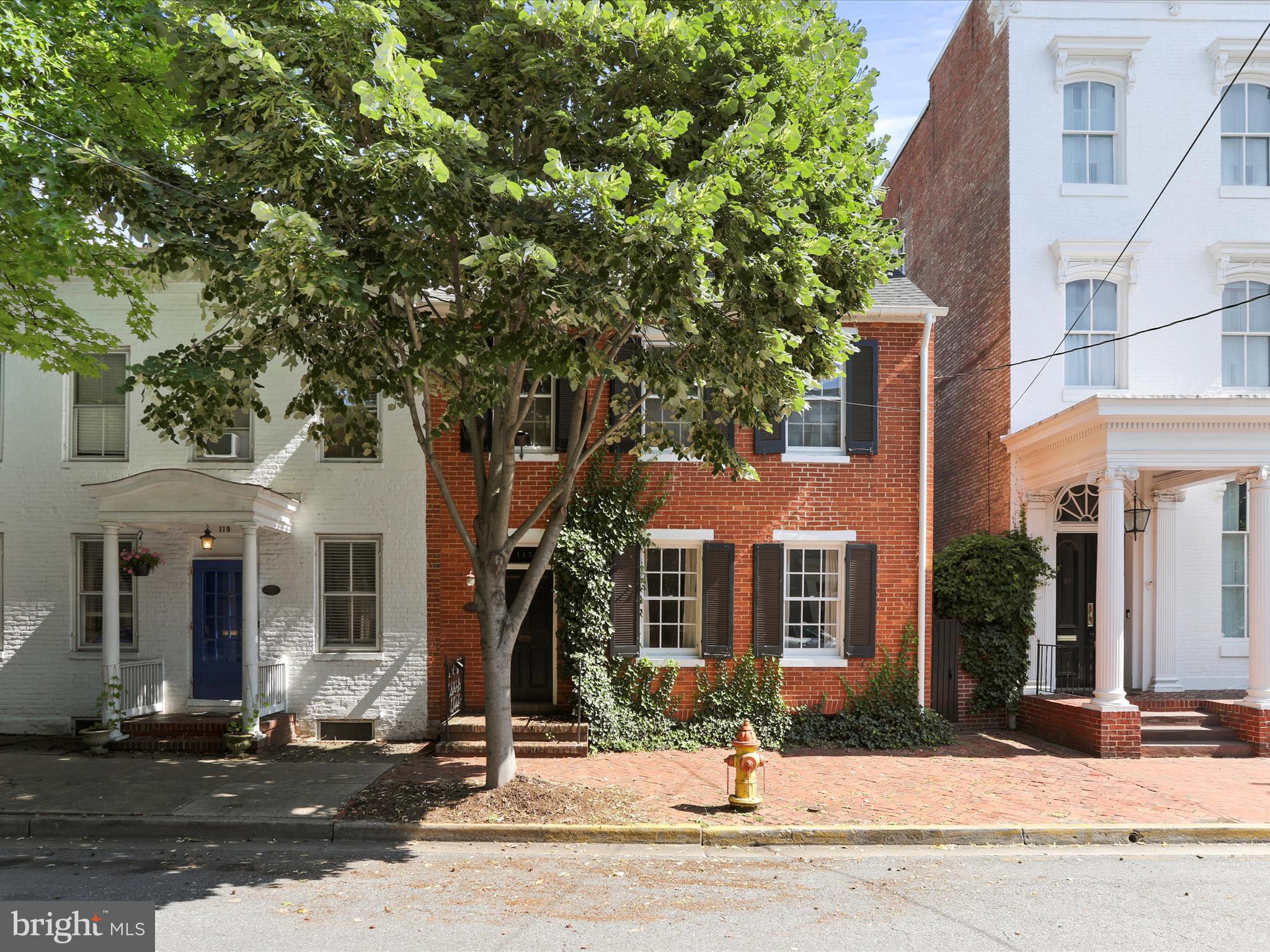 An exquisite opportunity to own this charming and meticulously maintained home just steps from Baker Park and only half a block from the heart of downtown Frederick. Brimming with character and timeless appeal, this home is sure to captivate every buyer who walks through the door.
Enter through the elegant foyer, highlighted by a stunning turned staircase. The home offers four spacious bedrooms and an updated full bath featuring new tile, a modern stand-up shower, and a stylish new sink. The main level half bath has also been updated with new flooring, decorative wallpaper, a vintage-style hand sink, and a unique picture box window that adds even more charm.
Freshly and professionally painted throughout (2022), this home includes a new roof replaced 50-year life (2022), two new central air conditioning (2022), tankless water heater installed (2022) and showcases refinished original wide-plank hardwood flooring that gleams across the entire residence. Additional features include custom window shutters, built-in shelving, and a covered balcony offering a cozy outdoor retreat. A walk-up, floored attic provides ample extra storage, also the basement with interior access comes equipped with a newly redone cement floor creating additional storage space.
The front formal living room welcomes you with a fireplace and leads seamlessly to the formal dining room, with a second fireplace where the updated lighting creates the perfect ambiance for entertaining. The functional eat-in kitchen offers generous counter and cabinet space, along with access to the rear yard and patio.
Enjoy peace and tranquility in the private, professionally landscaped backyard, complete with a brick hardscaped patio and privacy fencing. A deeded covered parking space just around the corner adds convenience and value. The rear walkway provides additional access directly to the street.
Take advantage of all that downtown Frederick has to offer, with dining, entertainment, and local attractions just a short walk away. This is a truly special property that blends historic charm with thoughtful updates in one of Frederick’s most desirable locations. You will not be disappointed.