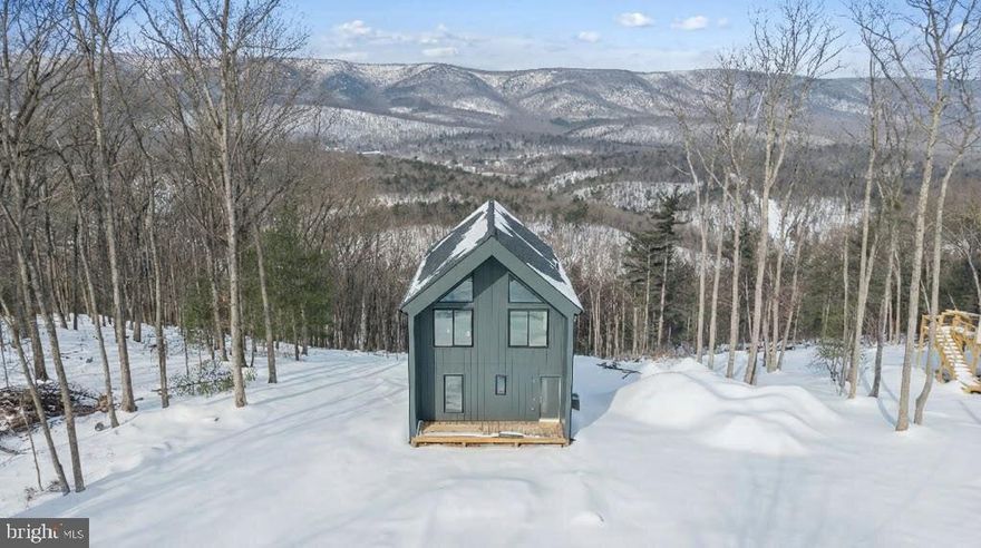 This newly built 2026 Scandinavian modern luxury home sits on 0.68 private acres along a scenic ridgeline setting, offering 3 bedrooms, 2.5 bathrooms, a finished basement, and elevated panoramic valley and mountain views. Properties in this immediate area are limited, and opportunities to own along this stretch of ridgeline do not come available often. Located just 5 minutes to Bryce Ski Resort and approximately 4 minutes to Lake Laura with canoe and paddleboard access, the home is positioned in the heart of Shenandoah Mountain recreation. The surrounding area benefits from four-season tourism appeal, including winter ski traffic, spring hiking, summer lake activity, and fall foliage visitors, along with proximity to wineries, caverns, and outdoor destinations that support consistent regional travel demand.
The elevated setting offers open sightlines and a sense of privacy, complemented by three expansive decks (two at 12' × 22' and one at 5' × 22'), a pre-constructed 400 sq ft amenity pad suitable for future hot tub or sauna installation (buyer to verify), a fire pit area, solar-lit stairs connecting deck levels, and Tesla-compatible EV charging. Inside, the home features clean Scandinavian-inspired design with floor-to-ceiling glass walls, open-concept living spaces, premium appliances, an upper-level loft with sweeping views, and a finished lower level that can function as additional sleeping space, recreation area, or flexible use room. A smart lock system supports convenient guest access and modern property management needs. Additional highlights include no HOA fees, private well service, a 3-bedroom rated septic system, and infrastructure in place for potential future amenity upgrades. With its combination of modern design, outdoor living space, and proximity to year-round recreation, this property presents a compelling option for buyers seeking a primary residence, second home, or short-term rental investment in a high-demand mountain setting.