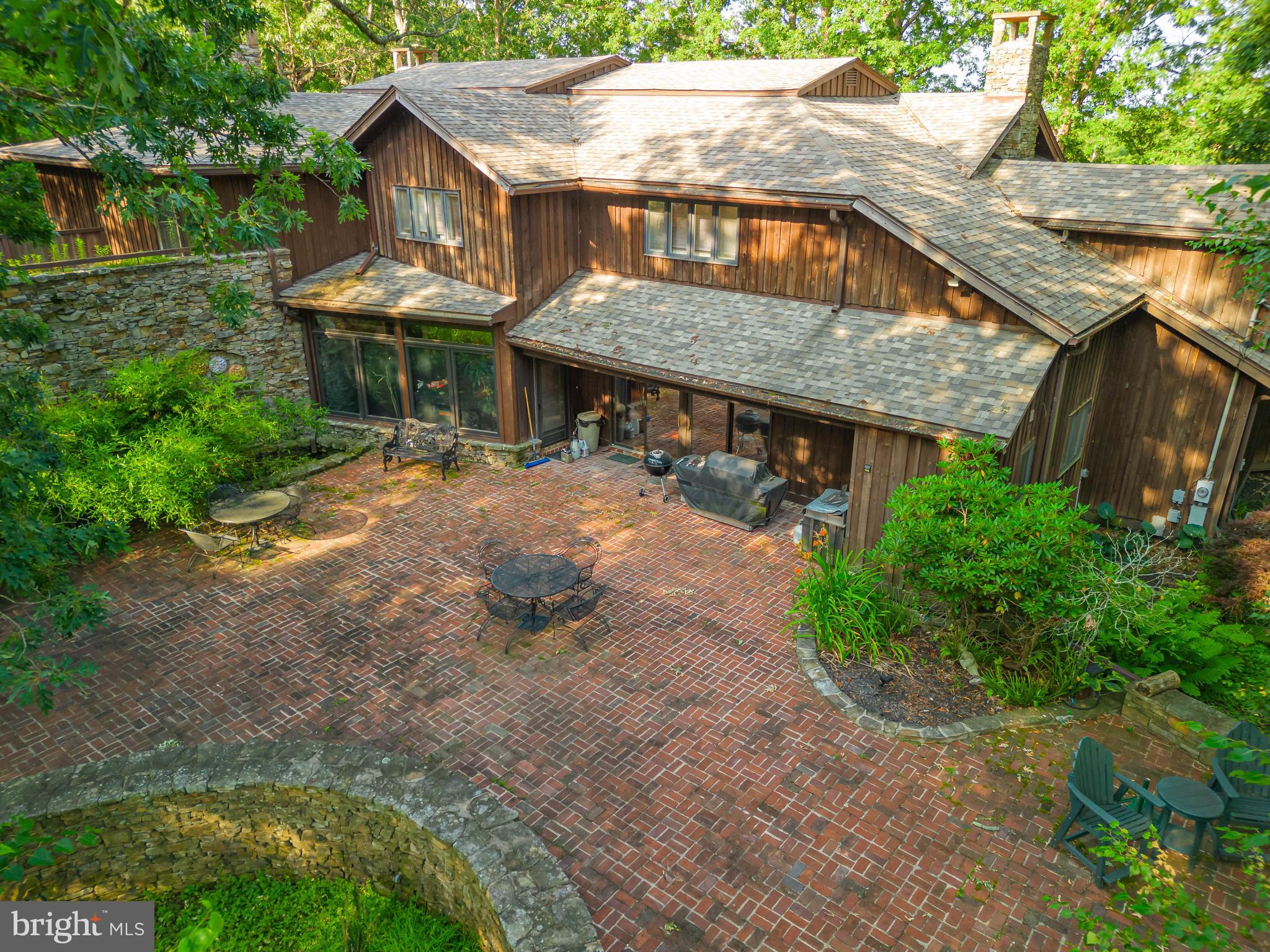 'Four Winds' is a Frank Lloyd Wright inspired masterpiece at Deep Creek Lake. Restored & renovated as recently as 2021, this 4/5BR home boasts 8000sf on nearly 5 acres of land. A small part of the home was converted to accommodate a successful medical practice - 2 patient rooms, bathroom & private office - which adds amazing potential to creatively 'work from home' in many professional fields and the elegant living areas easily double as a posh waiting room. There is an abundance of stone featured inside and outside of the property, essentially a modern castle. The exterior includes a brick courtyard , multiple outdoor living areas & covered porches, a master suite balcony with seasonal lake views, 5 total garage stalls (3 attached), a wraparound driveway with parking for 12+ vehicles, seasonal lake views from the rooftop balcony, covered gazebo & outdoor fire-pit. Inside, a modern a gourmet kitchen, Brazilian cherry floors, custom tile, elaborate dining room, 3 wood burning fireplaces + wood stove, multiple living rooms, 3 master suites, ornate carved doors, library and several over-sized storage rooms. Primary suite offers his + her bathrooms, sauna, wood burning fireplace and 'secret' spiral staircase descending to a sunken living room & basement level stone wine room. Other items of note: newer roof & updated mechanicals, whole house generator, multiple heat options, multiple instant hot water systems, Central AC, and much more. Must see to appreciate! Tax record shows year built of 1890, but owner indicates 800sf of the original farmhouse foundation was used as a foundation and the home is a totally rebuild circa 1976.