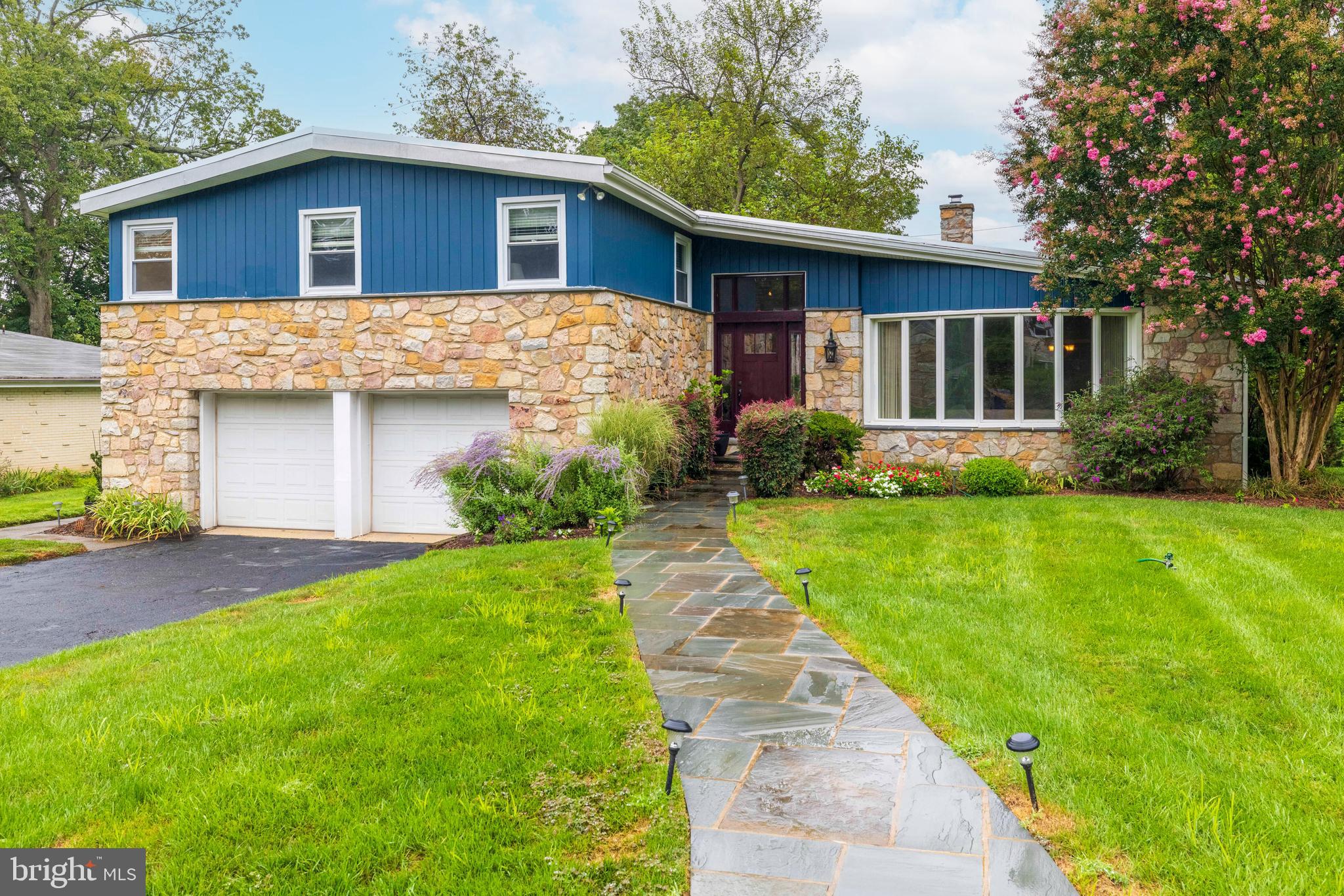 Situated in the highly sought-after Rydal neighborhood and just a short walk from downtown Jenkintown, this spacious stone-front home is ready for you to move right in. Nestled on a beautifully landscaped lot, it has been lovingly maintained and thoughtfully updated—an absolute gem. A charming stone walkway leads to a striking front entrance framed by glass panels, opening into a bright and inviting entry hall. The living room features gleaming hardwood floors, a vaulted wood-beamed ceiling, and a stunning curved wall of windows that fills the space with natural light. Modernized lighting transforms the space into a vibrant nighttime setting. From here, enjoy seamless flow into the formal dining room—perfect for hosting gatherings. Adjacent to the dining area, a versatile room with built-in cabinetry and direct access to the back patio offers the perfect space for a home office, den, or seamless indoor-outdoor entertaining. The large, renovated kitchen is a chef’s dream, offering abundant custom cabinetry, high-end appliances, a pull-out pantry, granite island and countertops, sky light, many ambient lighting options, and new sliding doors that lead to the multi-level patio and serene backyard. Step down into the beautifully finished lower level, where an expansive, light-filled family room awaits—featuring a striking stone fireplace wall, custom-built cabinetry, and direct access to the inviting grounds and stone patio, perfect for year-round entertaining or quiet relaxation. This level also includes an updated powder room, a well-equipped laundry/utility room with built-ins, and access to the oversized two-car garage. As a bonus, the finished basement offers additional space with a recreation room, multi-purpose bonus room, and ample storage. Upstairs, the primary suite serves as a peaceful retreat, featuring a recently remodeled bath with heated floors, dual skylights, double vanities, a luxurious walk-in tiled shower, and a separate soaking tub. A custom walk-in closet completes the suite. Three additional generously sized bedrooms and a full hall bath round out the upper level. Altogether, the home offers more than 3,400 square feet of thoughtfully designed living space. Located in the award-winning Abington School District, this exceptional home offers the perfect blend of indoor and outdoor living, all within easy reach of shopping, major roads, train access, and more. A rare find in a prime Rydal location—this is one you won’t want to miss!