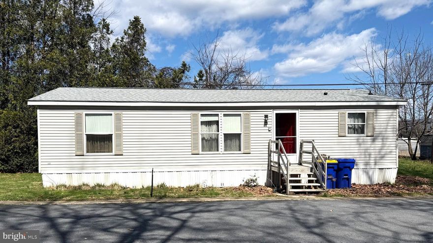 This conveniently located double wide features an open floor plan with a fully equipped kitchen, dining room and living room with an electric fireplace.  The primary suite with a full bath and walk- in closet is located on the opposite side of the house from the second bedroom and full bath.  A laundry room, with a washing machine and clothes dryer are located off of the kitchen.  New carpeting throughout!