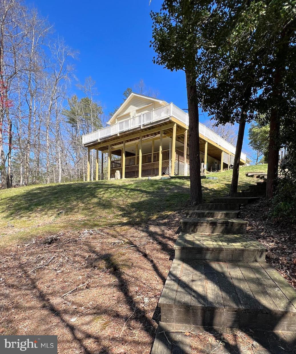 This waterfront home sits at the end of a cul-de-sac, is surrounded by mature trees, and has beautiful 180 degree views of Mill Creek. With the additional .3 acre adjacent lot included, you'll have over a half acre of privacy to enjoy the peaceful outdoors or even store your boat/recreational vehicles. The home features a new roof, gutter guards, expansive wrap around deck with retractable awnings and an extra shed for storage. Drop your kayak in at the floating dock, tie up at your private pier with 2'+ of water, or dock your boat at the marina just a few houses away. The two-car garage has plenty of storage, a work bench, extra electrical panel, and direct access to the kitchen for everyday convenience. The kitchen features hickory cabinets, quartz countertops, gently used stainless steel appliances and an oversized pantry and connect seamlessly to the open layout living and dining room areas. Down the hall is a full bath and oversized guest bedroom with double closet and wood floors. The primary bedroom has a dedicated sleeping area and adjacent 14 x 24 waterfront sunroom. This bright and airy sunroom has sliders on all sides that lead to the new deck and is the perfect place to begin and end your day. The ensuite bathroom has double sinks, tiled shower with sliding glass doors, and a walk-in closet. Throughout the home you'll find custom touches like the handmade railings and bar top, solid oak doors, hand turned crown molding, and quality Anderson windows. Downstairs is the laundry room, two spacious bedrooms, rec area and a second full kitchen with sliders to the waterfront. This ground level space doubles the size of the home and is perfect to use as a second entertaining area, in-law suite, or even a separate rental unit. All the major systems in the home have been updated: Septic - 2012, HVAC - 2019, 50 gallon water heater - 2021, new deck and roof in 2023, and more. The home is in great shape and ready for its next owners.