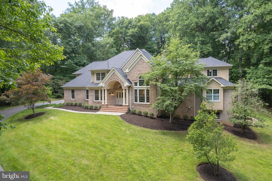 Fabulous brick transitional residence nestled on three wooded acres in the cul-de-sac community of Triadelphia Woods. Spacious and open flowing floor plan exudes elegance, quality design and workmanship. Opulence greets you upon entering the home with a grand foyer with two story vaulted ceilings, a formal living room with two story ceilings, a formal dining room dressed with all the trim, and newly refinished hardwood floors throughout the main level. A gorgeous, bright and new chefs-delight kitchen is dressed with 42" cabinetry, transoms, stainless steel appliances, quartz countertops and a breakfast room overlooking the back yard. Walk-out to screened-in porch and access the stylishly equipped butler's pantry, mudroom and half bath. The kitchen is adjoined to a magnificent great room adorned with two story ceilings, a brick wood-burning fireplace, ceiling fan, custom built-ins, and a wall of windows overlooking the walk-out to the beautiful rear stone patio and private yard.  The primary wing is housed on the main level and features a wet bar area with a wine cooler and ice machine, an office/library with a two-sided wood-burning fireplace shared with the primary bedroom suite. The primary suite features illuminated tray ceilings, plantation shutters on all the windows, a huge walk-in cedar California Closet, a laundry area, and a renovated bathroom with dual sinks, ceramic floors, separate tub and a huge walk-in shower. The second floor houses five huge bedrooms and three newly remodeled ceramic bathrooms, a second washer and dryer set and plenty of closet space. The fully finished walk-out basement offers a ton of flexibility as additional living space, an in-law or nanny suite or rental opportunity. The basement is equipped with at least one bedroom, a full bath, a spacious kitchenette with custom cabinetry, a family room with a gas fireplace, a billiard room, a media room with a projector and a 15' x 8' wall screen and stained concrete floors. There is also an additional room that has an abundance of natural light and walk-out to the patio and side yard. This lovely home provides great entertaining spaces inside and out. The property is served by private well and septic, propane gas heat, hot water and cooking, and 400 AMP electric service. Ample parking and storage is provided with an attached two car garage and a detached over-sized two car garage along with unfinished attic space that could be a future office, nanny suite or rental. 12' x 10' Log Playhouse also conveys.