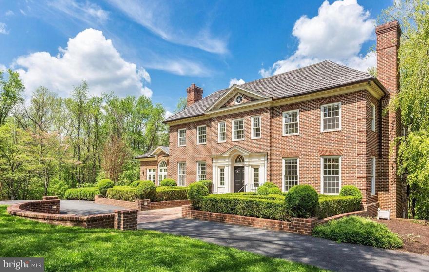 Nestled on a lushly landscaped 2.02-acre lot in the prestigious Mill Creek Landing community of Great Falls, this stately Georgian Colonial seamlessly blends timeless elegance with modern comfort and functional design. Classic architectural elements—high ceilings, marble flooring, wainscoting, a crystal drop chandelier, and four fireplaces—combine with thoughtful updates to create a home that exudes old-world grandeur while accommodating today’s lifestyle. Offering approximately 6,820 square feet of beautifully appointed living space across three expansive levels, this 6-bedroom, 4.5-bathroom residence is ideal for those who value space, sophistication, and privacy. A grand foyer with a dramatic dual staircase sets an elegant tone, flanked by formal living and dining rooms. A graceful elliptical archway leads into the inviting family room and adjoining gourmet kitchen, which features a cozy sitting area and direct access to the rear deck—perfect for al fresco dining and effortless entertaining. The formal living room opens to a sun-drenched great room, where oversized windows and a private balcony invite in natural light and scenic views. A richly paneled library, complete with custom built-ins and French doors to the deck, provides the ideal setting for a home office or quiet retreat. Upstairs, the luxurious primary suite offers a true sanctuary, featuring his-and-her walk-in closets and a spa-inspired bathroom. Three additional bedrooms provide generous accommodations, including a thoughtful layout with two bedrooms sharing a hall bath and one with its own private balcony. The walkout lower level is designed for both comfort and versatility, featuring a spacious recreation room with a wet bar, access to the garage, two additional bedrooms, and a full bathroom—perfect for guests, multigenerational living, or a dedicated workspace or gym. A mechanical room provides ample storage and utility. Surrounded by mature trees and lush landscaping, the property offers the tranquility of estate-style living with the added benefit of being bordered by 26 acres of protected parkland. Residents enjoy serene privacy, picturesque views, and direct access to the Difficult Run trail, which leads to the Potomac River and Great Falls National Park. Located in one of Great Falls’ most desirable neighborhoods, with convenient access to Washington, DC, Tysons, and Reston, this exceptional home presents a rare opportunity to enjoy the very best of Northern Virginia living—where timeless architecture meets everyday luxury.