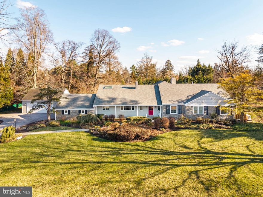 Set on a .71-acre level lot along one of Villanova’s most desirable neighborhood streets, this 5-bedroom, 3.5-bath ranch/Cape is surrounded by landscaped, highly usable grounds.

A covered front porch introduces the foyer and a large living room anchored by a fireplace framed with built-in cabinetry. Just beyond, a sunroom overlooks the rear grounds and gardens.

The dining room provides an inviting setting for gatherings and includes a large walk-in closet for serving pieces and entertaining supplies. Sliding glass doors extend the space to the patio, creating an easy connection for outdoor dining and entertaining.

The kitchen has vaulted ceilings, a large center island, cherry cabinetry, quartz countertops, and a breakfast area with sliding doors opening to the patio. A family room with gas fireplace connects seamlessly to the kitchen, creating a comfortable everyday gathering space.

The main level includes the primary suite with two walk-in closets and a bath with soaking tub and walk-in shower. A second bedroom on this level offers flexibility as a guest room or office. Additional main-level spaces include a laundry room, mudroom with vestibule to the two-car garage, and a separate office with built-in cabinetry and access to a third garage bay.

The second floor offers three additional bedrooms, including one with its own bath, along with a hall bath and a large recreation room. A large unfinished basement provides extensive storage.

Set among established homes in a sought-after Villanova neighborhood, the property combines a highly usable level lot, comfortable living spaces, and convenient access to the Main Line’s schools, shopping, and commuter routes.