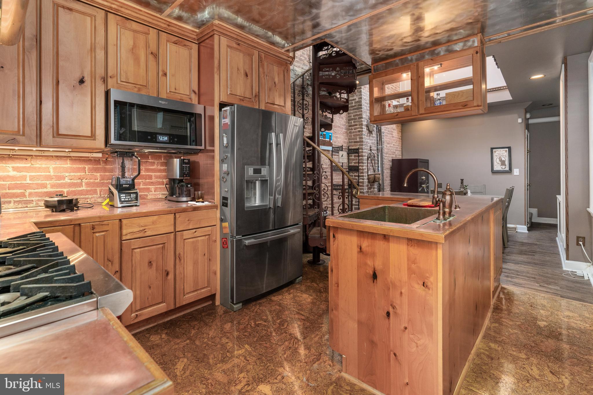This unique custom home exudes character at every turn! This artistically and industrial crafted design includes a variety of wood flooring through the main level, a large iron wood burning stove in the living room, and one staircase that leads to the second floor. The high open ceiling with a roof skylight streams sunlight down into the dining room that has a coal burning oven, and brick accent wall that goes from floor to ceiling with exposed piping. The dining room leads into a magnificent chef’s kitchen with copper countertops, copper farmhouse sink, and copper ceiling. The stainless steel appliances include a Wolf 6 burner stove with exhaust hood, and a metal wall backsplash and wood cabinets. There is a full bathroom on the main level and In the corner of the kitchen is the second spiral staircase that leads to a loft, Spacious bedroom and full bathroom with stacked washer and dryer. On the second level is the spacious primary bedroom with brick wall accents, and 2 closets. Outside in back in your own private oasis with a spacious patio surrounded by a tall wood fence where you can barbecue and entertain and make fond memories with family and friends. House is dual zoned. Close to restaurants, shopping and parks and highways. Schedule a tour today!
