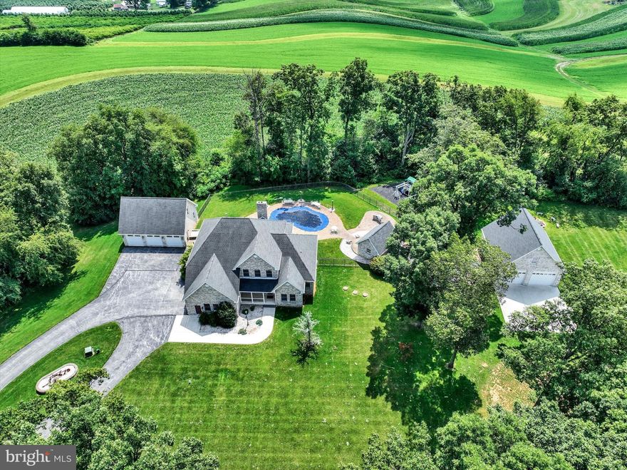 Fall in love  with the seclusion and convenience of this rural estate situated on 13+ acres of tranquil beauty. Country quiet, yet minutes to major arteries, shopping, restaurants, and most conveniences. Take this opportunity to escape the busyness of the world and delight in the peace and quiet Mother Nature provides. Enter the estate through brick pillars. Follow the tree-lined, lighted lane to a fabulous home surrounded by tall trees creating a screen of privacy, during summer months, and giving way to endless views, in the fall and winter months, when the leaves have dropped. Massive in design and amenities, the home showcases over 4200 sq ft of living space on two floors and an additional 1700+ in the lower level. The space and uniqueness of the floorplan allow for flexibility to customize your needs. The hub of the home is a great room open to a gourmet Rojahn Kitchen featuring stainless steel appliances including a 5’ wide freezer and refrigerator; a 6-burner gas stove with pot filler; double wall oven; and large island with seating for 6 barstools. A butler’s pantry/coffee bar is directly off the kitchen. A pantry and powder rm are adjacent to the kitchen. Doors open to a wonderful covered patio offering awesome extended living space overlooking a private backyard oasis. Park your vehicle, in the attached garage, and enter a spacious mudroom with endless possibilities for storage or even another garage. The current owners did a lot of redesigning of rooms to fit their needs. They converted the formal dining rm into an office and the living rm into a large laundry rm. Both could be converted back to their original uses. A primary suite with a recently remodeled luxury bath is also conveniently located on the 1st floor. The 2nd floor boasts five bedrooms and two full baths. If you don’t need five bedrooms, use it however you wish. Again, the uniqueness allows you to customize to fit your needs.  A spacious game room, full bath, exercise room, and storage room with a hidden room and a built-in bookcase, with a safe behind it, are located in the lower level. While this property offers outstanding indoor living space, it also has an incredible amount of outdoor living space. Fall in love with the large covered patio overlooking an in-ground pool surrounded by a Techno Bloc Patio. The saltwater pool has a 3-yr old liner, rough-in waterfall feature, and sliding board. The views are breathtaking! Adjacent to the pool is an outdoor kitchen, with bar stool seating, built-in grill and brick oven pizza oven. A detached pool house, with half bath and kitchen area make it ideal for entertaining and containing the mess. Even wet towels aren’t an issue, because you can toss them in your pool house dryer (not included). There is also an oversized playground near the pool. Along the side of the pool house is an outdoor shower. Go ahead, be the envy of your family and friends! If you are longing for garage space, you are sure to delight in the two brick, detached garages (5 bays total) on this property! We encourage you to bring the TOYS! You can also tinker for hours and not bother a soul! Both garages feature heat and walk-up 2nd flrs waiting to be finished into what you can dream. One garage has an oversized bay for the possibility of storing an RV or boat. Need a little down time from tinkering, shoot a few hoops on the basketball court in front of the garage.  Wanting more privacy, the owners purchased the adjoining 7+ acre lot, for 13+ total acres. It already has a well drilled giving you the opportunity to sell it as a residential building lot, if you prefer less acreage.  Additional features include whole house generator, alternate stand-alone wood heating system for the house, pool and 3-car garage; and a 5-zoned speaker system allowing you to enjoy music throughout the 1st and 2nd floors of the home and the outdoor patio. Truly an exceptional opportunity for one fortunate buyer!  AGENTS - Please read Agent Remarks!