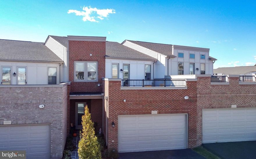 Meticulously maintained and highly optioned 4 bedroom/3 full bath brick front home, featuring a main level primary suite AND an upper level primary suite, with million dollar views of the community lake and clubhouse!  Birchwood is Loudoun County's #1 premier 55+ active adult community with amenities and activities that are second to none.   The main level of this home is wide open and perfect for entertaining, and features 10 foot ceilings, a gourmet kitchen w/ custom cabinetry, backsplash, lighting, pantry and quartz counters that opens to a flexible living and dining spaces and an in-wall gas fireplace.  A custom brick patio is just off the kitchen and is fully fenced and overlooks the lake.  A large main level primary suite with walk-in closet and luxury bath with two vanities complete this level.  There's also a laundry hook up on this level!  Take the stairs to the upper level that features a second primary suite, complete with custom walk in closet, tray ceiling, luxury bath w/ dual vanities, a walk-in shower, and soaking tub.  Just off this suite you'll find a roof top balcony with unobstructed views of the community lake and clubhouse.  The upper level also features 2 additional oversized bedrooms with walk in closets, another full bath, a large sitting room great for movie nights, custom laundry room, and another large rooftop deck for entertaining.  Wide plank LVP flooring throughout.  2 car garage plus plenty of guest parking!