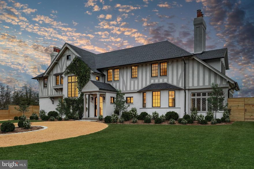 In the heart of Edgemoor, Bethesda’s preeminent residential community, is 7611 Fairfax Road, a faithfully reinterpreted Tudor estate blending the utmost in modern luxury with classical workmanship and tasteful architectural finishes. Sited on a 1/2 acre prime level lot, merely three blocks to Downtown Bethesda’s glass towers, the home represents a once-in-a-lifetime, no compromises opportunity. With prominent curb appeal, the facade evokes a sense of old world charm with its contrasting timbered trim and artful gables. The elegant arched glass and iron front door reveals an elegant reception hall and tucked away main staircase, introducing a reconfigured floor plan spanning a generous 7,600 square feet. In the nod to tradition, formal living and dining rooms flank the vestibule in a classic center hall layout. Both formal spaces are embassy-sized — the former spanning a full 30 feet in length — and feature roaring fireplaces. Off the living room is an intimate sunroom opening up to the grounds. In the center of the main level is a stunning chef’s kitchen with custom cabinetry and an imported commercial Italian oven. Stackable glass sliders open to reveal the patio and bring the outside in. Double doors part ways to reveal the main level primary suite’s private sitting room. The adjacent sleeping area features a soaring cathedral ceiling and offers direct outdoor access. The ubiquitous luxury amenities – marble-clad bath with dual vanities, freestanding tub, glass shower, enclosed water closet, and designer fixtures, as well as twin walk-in dressing rooms make the suite a secluded oasis. An expansive mudroom and access to the attached three car garage complete the main level. On the upper level is a second primary suite featuring a private fireplace and two truly expansive dressing rooms. Its ensuite bath mirrors the main level primary suite’s in both opulence and amenities. Three additional secondary bedrooms, each with ample closet space and marble ensuite baths, complete the upper level. A set of stairs accesses extensive storage space in the attic, while more storage space is provided in the lower level. During the transformation, the estate was taken down to the studs and contains all new HVAC, plumbing electrical, flooring, roof, and windows to establish a truly modern residence. Outside, nearly a half acre of flat, usable space affords expansive grass lawns and total privacy while remaining virtually unheard of in such a central location. Situated within walking distance to shops, restaurants, parks, entertainment and belonging to award-winning schools, 7611 Fairfax Road establishes itself as a leading estate in one of the Capital Region’s most sought after locations.