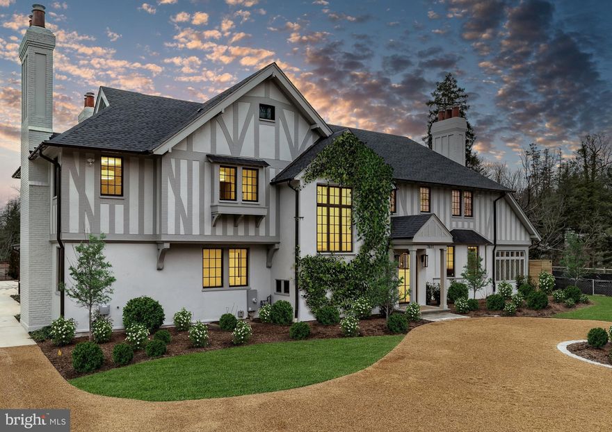 In the heart of Edgemoor, Bethesda’s preeminent residential community, is 7611 Fairfax Road, a faithfully reinterpreted 1915 Tudor estate blending the utmost in modern luxury with classical workmanship and tasteful architectural finishes. Sited on a 1/2 acre prime level lot, merely three blocks to Downtown Bethesda’s glass towers, the home represents a once-in-a-lifetime, no compromises opportunity. With prominent curb appeal, the facade evokes a sense of old world charm with its contrasting timbered trim and artful gables. The elegant arched glass and iron front door reveals an elegant reception hall and tucked away main staircase, introducing a reconfigured floor plan spanning a generous 7,600 square feet. In the nod to tradition, formal living and dining rooms flank the vestibule in a classic center hall layout. Both formal spaces are embassy-sized — the former spanning a full 30 feet in length — and feature roaring fireplaces. Off the living room is an intimate sunroom opening up to the grounds. In the center of the main level is a stunning chef’s kitchen with custom cabinetry and an imported commercial Italian oven. Stackable glass sliders open to reveal the patio and bring the outside in. Double doors part ways to reveal the main level primary suite’s private sitting room. The adjacent sleeping area features a soaring cathedral ceiling and offers direct outdoor access. The ubiquitous luxury amenities – marble-clad bath with dual vanities, freestanding tub, glass shower, enclosed water closet, and designer fixtures, as well as twin walk-in dressing rooms make the suite a secluded oasis. An expansive mudroom and access to the attached three car garage complete the main level. On the upper level is a second primary suite featuring a private fireplace and two truly expansive dressing rooms. Its ensuite bath mirrors the main level primary suite’s in both opulence and amenities. Three additional secondary bedrooms, each with ample closet space and marble ensuite baths, complete the upper level. A set of stairs accesses extensive storage space in the attic, while more storage space is provided in the lower level. During the transformation, the estate was taken down to the studs and contains all new HVAC, plumbing electrical, flooring, roof, and windows to establish a truly modern residence. Outside, nearly a half acre of flat, usable space affords expansive grass lawns and total privacy while remaining virtually unheard of in such a central location. Situated within walking distance to shops, restaurants, parks, entertainment and belonging to award-winning schools, 7611 Fairfax Road establishes itself as a leading estate in one of the Capital Region’s most sought after locations.