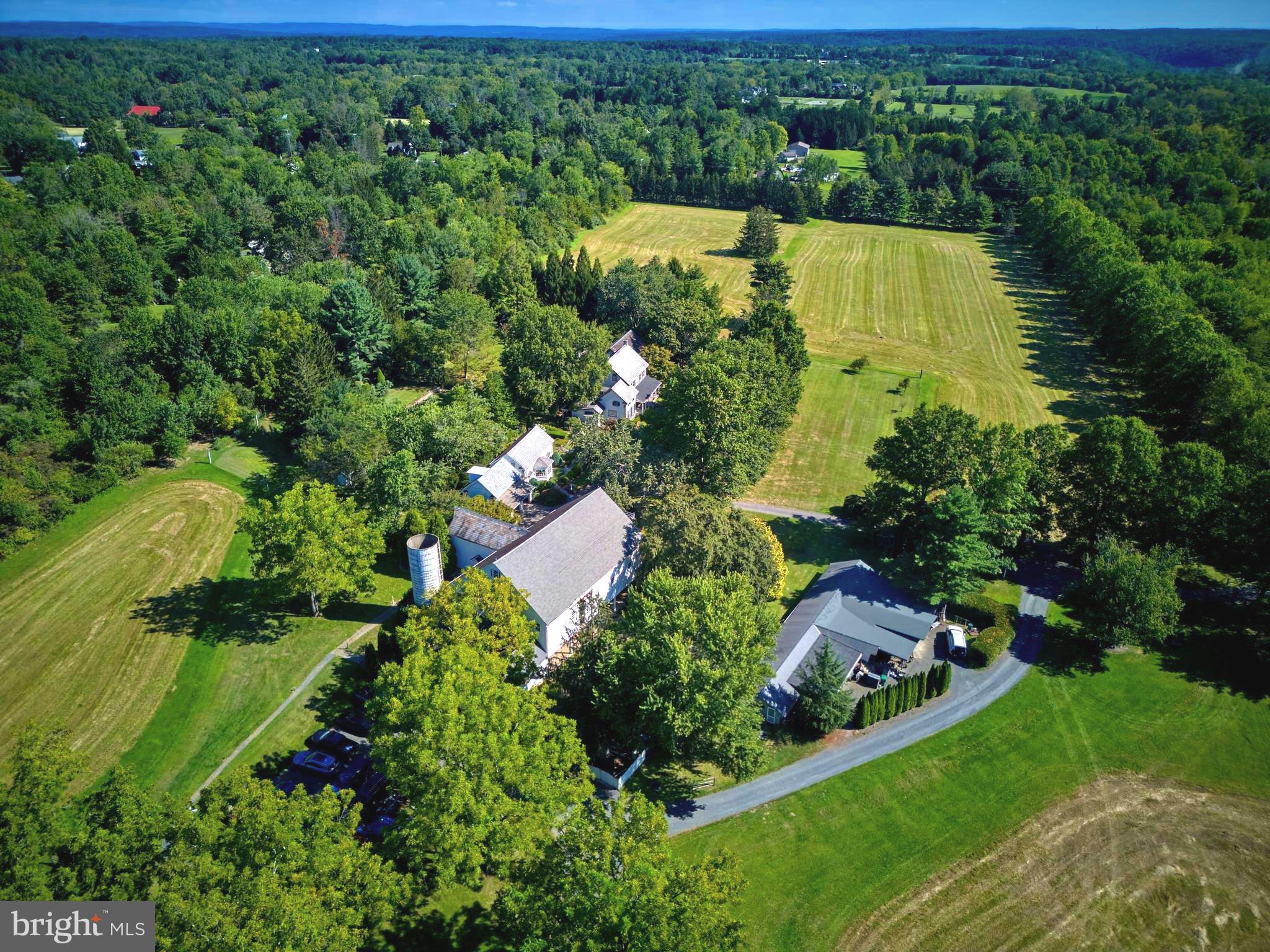 More than 800ft down a tree lined country drive way, flanked by open fields and dotted with freshly harvested hay bales the exciting glimpse of Silver Buttons Farm begins to emerge. This quiet and sophisticated compound is reminiscent of the estates in Greenwich and Darrien, Connecticut. As you pass through the gates, you enter a formal auto-court with a panoramic view of the stately and quintessential Bucks County farmhouse, 18th century bank barn with a separate art studio with north-facing window over the two car garage with guest suite. The initial portion of the main dwelling was built in the late 1700s and has evolved into the present 5700 sq/ft home. All of the rooms on the main floor have 9ft ceilings and on the 2nd floor rise to 14ft in the primary suite. The modern kitchen has a Garland stove and corresponding high end stainless appliances . The kitchen is eat-in, with adjacent formal dining room. The highlight of the first floor is a 1000 sq/ft solarium with three walls of windows that look out at the pool, pool house and fields. The home has been meticulously maintained while preserving the age-old patina on the floorboards. The main floor millwork dates back to 1810. The bedrooms on the 2nd floor range from 1000sq/ft to down to the smallest of the original 18th century home. There are 3 full baths on the 2nd floor and a powder room off the foyer on the main floor. Just 50ft away is the former carriage barn, which has been transformed to a modern office with bathroom and a separate guest suite above with full bath. The fully reimagined and beautifully lit, party barn with heated dining area just across the motor court has a commercial size kitchen, full service wet bar and three bathrooms. Follow the sweeping staircase to the 2nd floor with additional bar adjacent to the dance floor. The home is surrounded by a lush and serene landscape with fieldstone walls and impressive gardens. To the rear of the property is a rectangular lily pond. At one end of the pool is a Williamsburg-inspired pool house with French doors and slate roof. At the other is a large pergola with mature wisteria. Silver Buttons Farm is the estate that you are looking for.