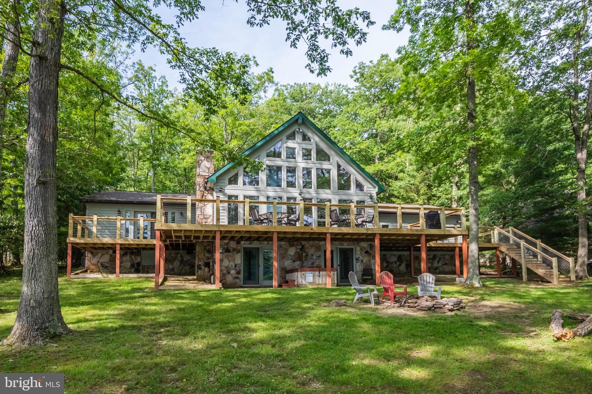 4BR, 4BA lakefront chalet with 124' of remarkably flat waterfront AND western exposure! Nearly one full acre in size, dockslip, big lake views inside and out, lakeside firepit, 3300sf home with over $200k in recent renovations. Impressive stacked stone fireplace. Recent upgrades: roof replaced 2 years ago, new 1400sf trex deck, updated kitchen, bathrooms, custom tile, flooring, updated furnishings and more! Plenty of parking with an oversized, wrap-around driveway and attached garage. Excellent location on coveted Rock Lodge Rd. with deep water and on the main body of Deep Creek Lake. Established vacation rental 'Over the Rainbow'.