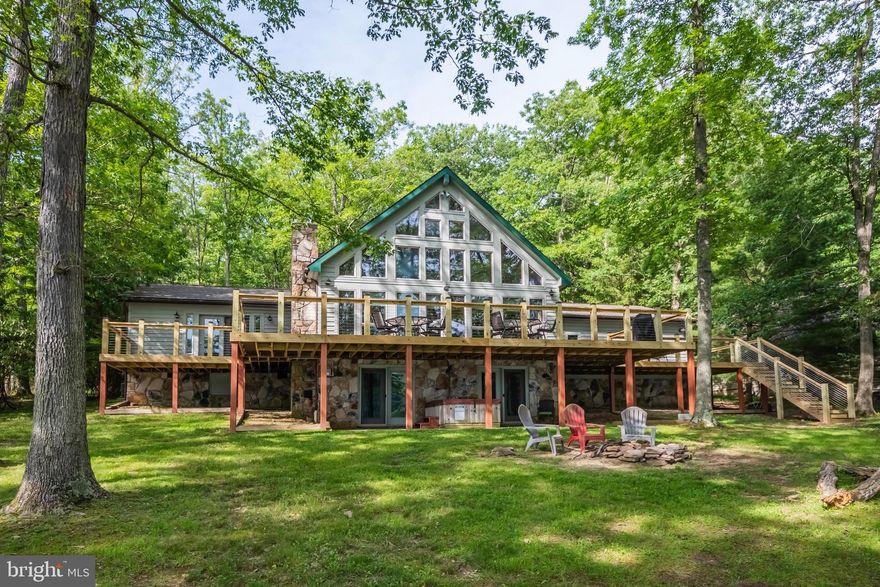 4BR, 4BA lakefront chalet with 124' of remarkably flat waterfront AND western exposure! Nearly one full acre in size, dockslip, big lake views inside and out, lakeside firepit,  3300sf home with over $200k in recent renovations. Impressive stacked stone fireplace. Recent upgrades: roof replaced  2 years ago, new 1400sf trex deck, updated kitchen, bathrooms, custom tile, flooring, updated furnishings and more!  Plenty of parking with an oversized, wrap-around driveway and attached garage. Excellent location on coveted Rock Lodge Rd. with deep water and on the main body of Deep Creek Lake. Established vacation rental 'Over the Rainbow'.