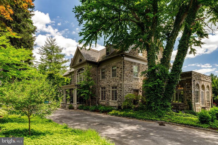 Immerse yourself in the storied grandeur of 1221 Lafayette Rd, an architectural jewel spanning 9,388 square feet, originally constructed in 1895. This remarkable residence exemplifies the pinnacle of historic craftsmanship, with every detail meticulously preserved to honor its legacy. Rich woodwork, ornate plaster motifs, and opulent marble and wood fireplace surrounds are woven throughout, creating an atmosphere of refined elegance that echoes through the centuries.
Set within a tranquil suburban enclave, the estate offers seamless access to Center City, the Philadelphia Airport, and the vibrant Main Line corridor, home to charming boutiques, fine dining, and cultural attractions. French doors punctuate the home’s façade, gracefully leading to a sprawling stone terrace. From here, the vista unfolds—a glittering swimming pool framed by manicured gardens, with mature centennial and blossoming trees dotting the landscape, enhancing the estate’s secluded, park-like allure. Privacy is paramount, with fencing that secures the grounds while blending harmoniously with the natural surroundings.
Upon entry, the grand center hall makes a striking first impression, featuring limestone, oak, parquet, and marble floors that carry throughout the home. The architectural flow transitions effortlessly between formal entertaining spaces and intimate retreats, offering both grandeur and comfort.
The formal living room stands as a testament to the home’s historic pedigree, showcasing original paneling sourced from an 18th-century German castle, crowned with intricate moldings. A stately wood-burning fireplace anchors the space, surrounded by built-ins and flanked by twin sets of French doors opening to the terrace. Adjacent is the sunlit game room, where arched windows on three sides bathe the space in natural light, making it an ideal setting for hosting poker nights or musical soirées.
The dining room exudes timeless sophistication, with wood floors underfoot, a handsome fireplace, and a ceiling adorned with delicate plaster flourishes. A richly paneled study offers a sanctuary for contemplation, with built-ins, a hidden passage to the kitchen, and a wood-burning fireplace adding to its charm. Just beyond, the family room beckons with its cozy ambiance, providing a restful space for relaxation.
At the heart of the home lies the kitchen, thoughtfully updated with modern amenities. A generous island with a prep sink anchors the space, accompanied by a six-burner Viking gas cooktop, dual wall ovens, a double Electrolux refrigerator, and a breakfast nook. French doors extend the kitchen into the outdoor living space, offering a harmonious blend of indoor-outdoor dining.
Ascending to the second floor, the primary suite reveals a serene retreat with wood flooring, French doors leading to a private balcony, and a walk-in closet. A sitting area connects to the sleeping quarters via a Jack-and-Jill bathroom, while the ensuite bath boasts granite-topped double vanities, a soaking tub, and a stone-tiled shower with a built-in bench, all illuminated by abundant natural light. The remaining second-floor bedrooms are equally charming, complemented by an expanded laundry room equipped with a Samsung washer and dryer, dual sinks, and balcony access.
On the third floor, a versatile landing area—spotlit and framed by warm wood floors—leads to Bedroom 5, a former dance studio complete with mirrored walls and ballet bars, offering endless possibilities as a fitness studio or creative space.
Outside, the estate continues to impress. The stone terrace, which stretches along the length of the house, serves as the perfect venue for grand outdoor gatherings. Adjacent to the kitchen, a more intimate patio with fenced flooring provides a serene spot for morning coffee or al fresco dinners. The pool, complete with a spa, is accessed via a flight of elegant stone steps, creating a picturesque focal point within the meticulously landscaped grounds.
1221 Lafaye