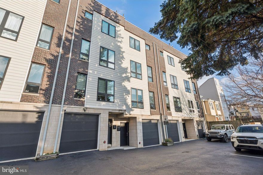 Welcome to 3828 Manor Street, a beautifully maintained townhouse in the heart of Manayunk, featuring 4 bedrooms, 3.5 bathrooms, 2-car parking, and elegant luxury finishes throughout. This home boasts over 3,000 sq ft of modern living space with an open concept main floor, gleaming hardwood floors, oversized windows, abundant closet space, high-end bathroom finishes, and one year remaining on the 10-year property tax abatement. The main level is bright and open with floor-to-ceiling west-facing windows, a dining area, and a spacious living room that opens to a private front porch. The recently updated kitchen features white shaker cabinets, a center island with seating, quartz countertops, stainless steel appliances (refrigerator, gas range, range hood, microwave drawer, dishwasher, and wine fridge), a pantry, under-cabinet lighting, and sleek black fixtures. Upstairs, you’ll find two large bedrooms including a guest suite with en-suite bath, an additional hall full bath, laundry area, and storage. The 3rd floor primary suite is a true retreat with a private balcony, expansive walk-in closet, and a spa-inspired bathroom featuring a freestanding soaking tub, oversized step-in shower, Porcelanosa double vanity, and separate water closet. A pilot house opens to a spectacular two-sided roof deck, offering skyline views and breathtaking sunsets to the west, while an east-facing space provides the perfect setting for entertaining. A custom wet bar with sleek quartz countertops enhances the experience, making rooftop gatherings effortless. The lower level offers a fourth bedroom or flex space—perfect for a home office, gym, media room, or guest quarters. Parking is easy with a 1-car attached garage and an assigned off-street space. The garage is equipped with a 208-volt outlet and a 50-amp breaker, perfect for charging your electric vehicle. Located on a quiet side street just steps from Main Street Manayunk, regional rail, major highways, Kelly Drive, Center City, the suburbs, and multiple parks and trails.