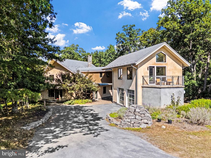 PRICE REDUCED! Where Architectural Digest meets mountain serenity-welcome to 79 Marigold Way.
A modern eco-luxe retreat nestled in the exclusive Broomgrass community, this 3-bedroom, 4-bath passive solar masterpiece was designed by acclaimed natural architect Sigi Koko and custom-built over two years with impeccable attention to craftsmanship, sustainability, and sensory living.

At the heart of the 3,479 sq ft residence lies a dramatic two-story stone fireplace, with a "Rumford" firebox designed to reflect heat into the room. 180 tons of hand quarried limestone salvaged from a pre-Civil War era barn foundation in Shepherdstown was transported for the construction of the fireplace, retaining walls, and stone features, such as the cairn at the top of the driveway. Blacksmiths by local artisans at Anvil Works hand forged the fireplace screen.  The open-concept living and dining space is anchored by hand-troweled, radiant-heated concrete floors and floor-to-ceiling windows that frame the seasonally shifting landscape and fill the home with natural light.

The chef’s kitchen is as durable as it is refined, featuring Lukrete concrete countertops, custom bamboo cabinetry by Cohen Custom Cabinetry, natural-edge walnut accents, and eco-conscious finishes. Just steps away, a curved architectural wall leads to a cozy family room designed for quiet evenings and uninterrupted streaming, thanks to high-speed connectivity from nearby towers.

The first-floor primary suite is a sanctuary in its own right, with an ensuite bathroom featuring double terrazzo sinks, an overhead rain showerhead, and a site-poured Japanese soaking tub crafted from concrete and polished to a soft finish- a sculptural centerpiece grounded in wellness and intentional design.

Upstairs, two additional bedrooms share a cleverly designed bath featuring a space-saving sliding glass shower that can be accessed from either side, perfectly balancing function and flow. Both rooms feature sustainable cork flooring, soft underfoot, continuing the eco-conscious narrative. Both bedrooms offer captivating sightlines to the lush, living roof, an eco-friendly feature that acts as a thermal insulator to reduce energy consumption. A cozy second floor sitting nook provides access to the cantilevered balcony where you can enjoy the surrounding landscape or gaze at the night sky. 

From a glass walkway, you are led through an interior bridge to a separate studio apartment, complete with a full kitchenette, tiled shower, and a private balcony overlooking North Mountain and fields.

Outdoors, every detail has been considered: a deep covered patio with a wood-burning fireplace, living roof blooming with sedum, and garden paths lined with lavender, hellebores, phlox, and mature crepe myrtles. Panoramic views of Sleepy Creek and North Mountain complete the immersive natural experience. This is a home where sustainable luxury meets editorial-worthy design. Geothermal heating and cooling, radiant floor heating, and passive solar orientation work in harmony with thick straw-bale wall insulation to create year-round  comfort with reduced energy consumption. Clay and lime plaster offer both tactile elegance and natural breathability. Douglas Fir moldings and trim elevate every surface with warm tones. An underground water collection cistern, along with bio-kinetic septic system, provides landscape irrigation. Broomgrass is a 325 acre community comprised of 16, one-acre properties with shared ownership of the remaining 309 acres of pastures and woodlands in a preservation trust. Shared amenities include a large pool, hot tub, sauna, pavilion, and kitchen for community gatherings. A true unicorn property, seamlessly blending design pedigree, environmental ethos, and  editorial appeal.