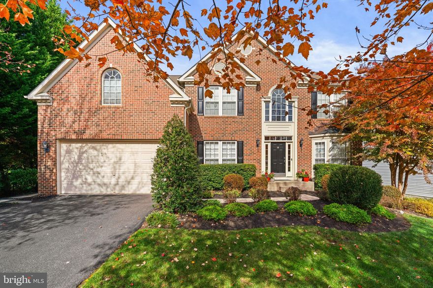 Tucked away in the prestigious and serene Dennis Preserve, this exceptional Colonial offers timeless elegance, refined finishes, and striking curb appeal. A classic brick façade accented by black shutters is beautifully framed by lush, mature landscaping, creating a welcoming and impressive first impression.

Inside, rich hardwood floors flow throughout the gracious interior, complemented by a traditional yet thoughtfully designed floor plan. Custom moulding, wainscoting, and decorative columns add warmth and sophistication at every turn. The main level opens with a dramatic two-story foyer, flanked by a formal living room with bay windows and a formal dining room adorned with an elegant chandelier, ideal for hosting memorable gatherings. Just beyond, French doors lead to a private study or home office with custom built-in bookcases, along with a conveniently located powder room.

The heart of the home is the expansive family room, featuring stunning coffered ceilings, plush carpeting, oversized windows, and a cozy fireplace. Seamlessly connected is the beautifully appointed eat-in kitchen, offering a large center island with breakfast bar seating, statement pendant lighting, a stylish backsplash, a pantry, abundant cabinetry and counter space, and stainless steel appliances, including double ovens. The adjacent breakfast room impresses with cathedral ceilings, panoramic windows, and direct access to the outdoor living spaces. A functional mudroom/laundry room provides convenient access to the garage.

Upstairs, four generously sized carpeted bedrooms and three full bathrooms offer comfort and privacy. The luxurious owner’s suite is a true retreat, featuring a tray ceiling, a sitting area, and two walk-in closets leading to a spa-like ensuite bath with a jetted soaking tub, dual vanities, a separate shower, and a private water closet. Two secondary bedrooms share a bath, each with its own private sink/vanity area, while the fourth bedroom enjoys its own attached bath.

The fully finished walk-up lower level expands the living space with a recreation room complete with a full wet bar, a built-in writing station, a potential fitness space, a full bathroom, a versatile bonus room ideal for guests, and ample storage.

Outdoor living is equally impressive, with a deck that steps down to a stunning paver patio featuring a curved retaining wall, surrounded by mature trees for shade and privacy. The expansive backyard backs to wooded views and includes a storage shed, meandering stepping-stone paths, and lush landscaping that wraps the home in natural beauty.