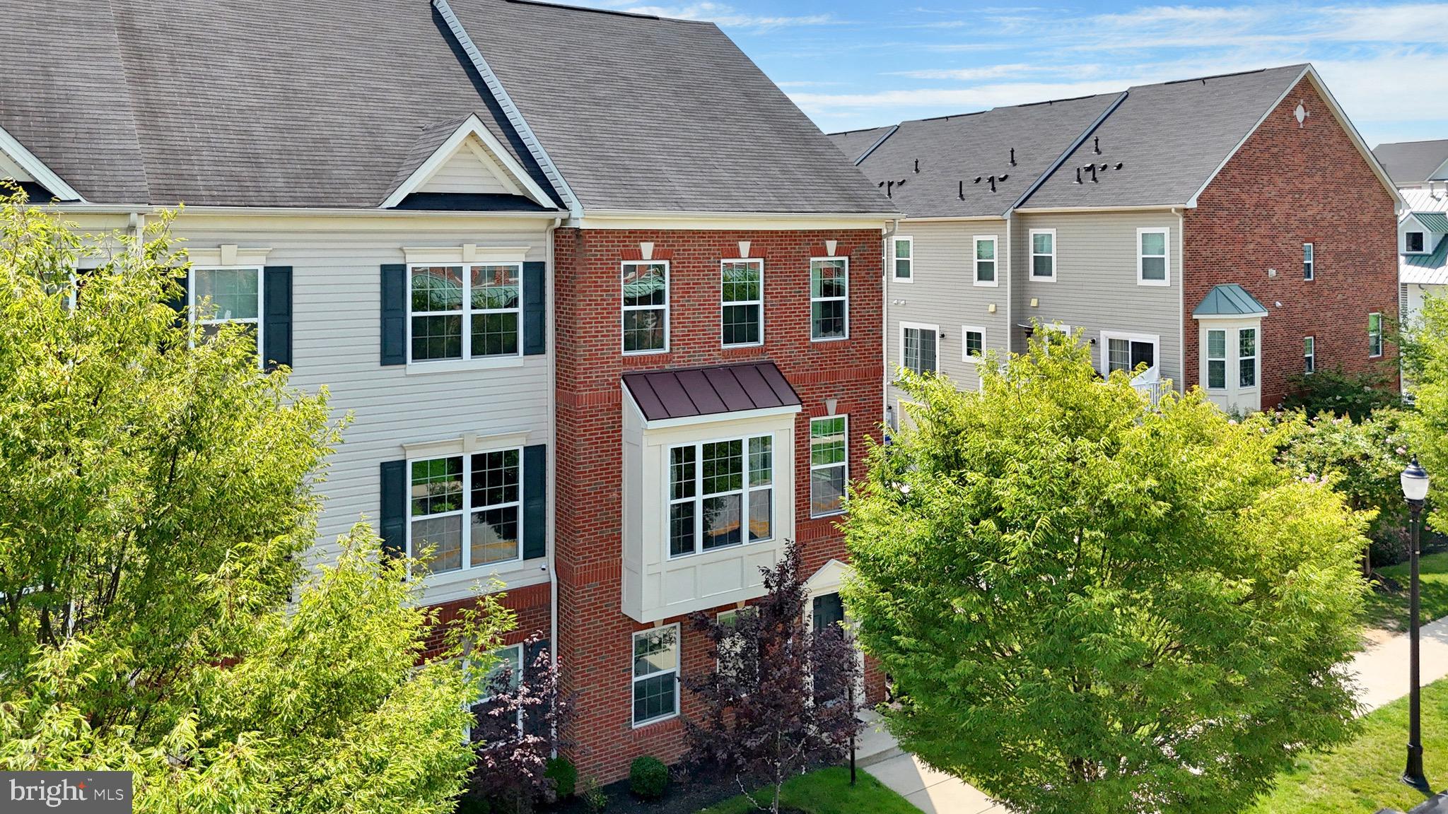 Welcome to 7049 Banbury Drive, a beautifully appointed interior townhome nestled in the sought-after Oxford Square community of Hanover, MD. This refined residence offers the perfect blend of timeless elegance, modern convenience, and thoughtful design. The exterior showcases low-maintenance vinyl siding framed by meticulously landscaped grounds, offering an inviting first impression. Inside, a sunlit foyer welcomes you with gleaming engineered hardwood floors that flow into a spacious recreation room featuring a striking accent wall and a half bathroom. This flexible space easily doubles as a guest suite or entry-level bedroom. Additional features on this level include tailored window treatments, a custom-built mudroom with ample storage, and direct access to the oversized two-car garage. The main living level is a true centerpiece, where freshly painted walls, detailed crown molding, and rich hardwood floors create a sophisticated ambiance. The gourmet kitchen is outfitted with 42” Snow White cabinetry, granite countertops, a large island with bar seating, stainless steel appliances including a gas range, built-in microwave, and refrigerator, and a cozy coffee nook. Step outside to a private TREX deck—perfect for morning coffee or evening entertaining. A charming butler’s pantry leads to an expansive walk-in pantry, while a stylish powder room completes this level. Upstairs, the private quarters include a serene owner’s suite with plush carpeting, elegant window treatments, a generous walk-in closet, and a spa-inspired en-suite bath featuring dual granite vanities, a glass-enclosed walk-in shower, and a private water closet. Two additional bedrooms, a full bathroom with tiled tub/shower, a linen closet, and a full-size laundry area complete the upper level with ease and comfort. This home was built with energy efficiency at its core, boasting a 92% efficient gas heating system, high-efficiency HVAC, Tyvek HomeWrap, dual-pane Low-E windows, premium insulation, sealed air barrier and ductwork, a fully insulated steel garage door, newly replaced water heater, brand new dishwasher and durable 20-year architectural shingles ensuring year-round comfort and cost savings. Perfectly located for effortless commuting, this home is just minutes from major highways like 295–Baltimore-Washington Parkway & Route-100, with quick access to both Baltimore, Washington, D.C., Arundel Mills, BWI Airport and so much more. Residents enjoy the convenience of a private community shuttle to the Dorsey MARC Station and are zoned for some of Howard County’s top-rated schools with the Elementary & Middle School in the community. The Oxford Square community further elevates the lifestyle with resort-style amenities including a sparkling swimming pool, state-of-the-art fitness center, basketball courts, playfields, playgrounds and lush open green spaces. Experience luxury, comfort, and community all in one extraordinary home. Don’t miss this rare opportunity—schedule your private showing today.