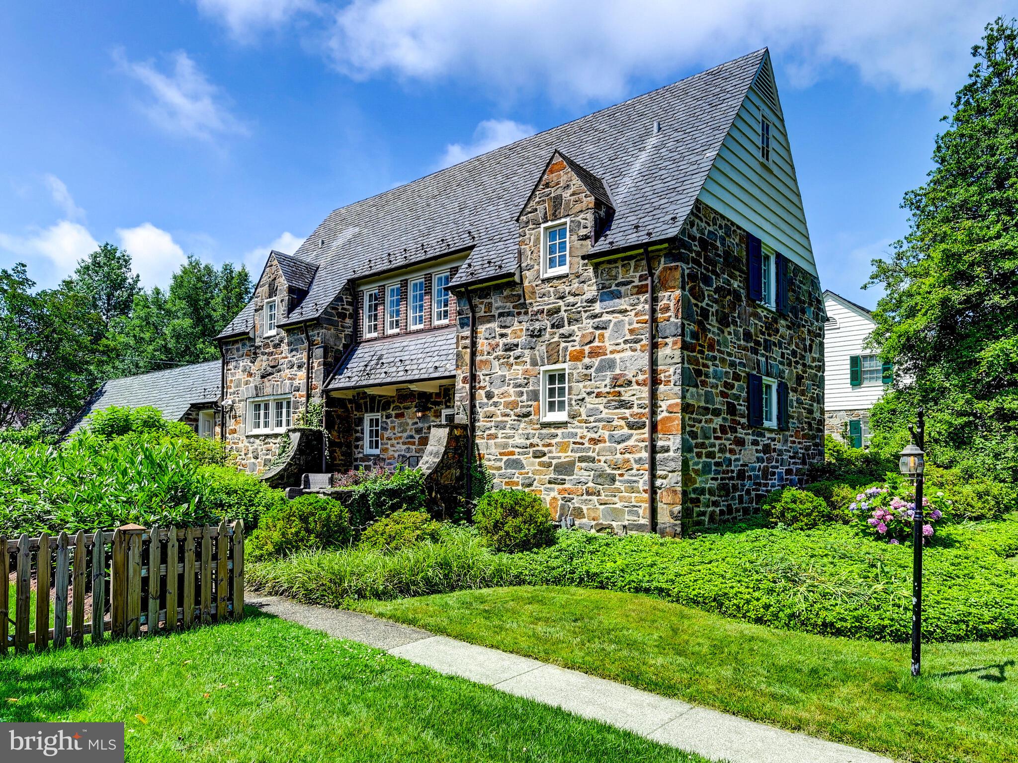 Nestled on one of Homeland's most coveted streets, this 1928 stone Palmer & Lamdin jewel masterfully blends architectural distinction with thoughtful modern updates. From the moment you ascend the stone entry terrace, framed by blooming gardens, you're embraced by timeless charm and a sense of place.
Lovingly maintained, the home offers enduring elegance and a lifestyle designed for both comfort and grace.
The main level features a well-appointed kitchen with stainless steel appliances and granite countertops, seamlessly uniting form and function. Just steps away, a spacious pantry and mudroom add convenience and practical storage. The dramatic 27' x 16' living room captivates with its soaring 14' cathedral ceiling, original wood floors, and a stunning wall of windows and doors that bathe the space in light. French doors from both the living room and sunlit dining room open to an extraordinary fieldstone patio, an ideal setting for seamless indoor-outdoor entertaining. The main level also offers a private primary suite, enhanced by a beautifully renovated en suite bath (2019), designed with comfort and accessibility in mind.
Upstairs, a cozy sitting area with a second fireplace provides a peaceful retreat, along with two additional bedrooms-each with its own private bath. The third level features a versatile fourth bedroom or home office, offering flexibility to suit your needs.
The pristine lower level offers ample storage and potential for future finished space. Recent updates include roof and chimney work (2017), water heater(2017), HVAC systems (2023 & 2024), and a new boiler (2023).
Set against a backdrop of lush landscaping and romantic stone architecture, this exceptional residence is both a tribute to classic craftsmanship and a sanctuary for modern living.