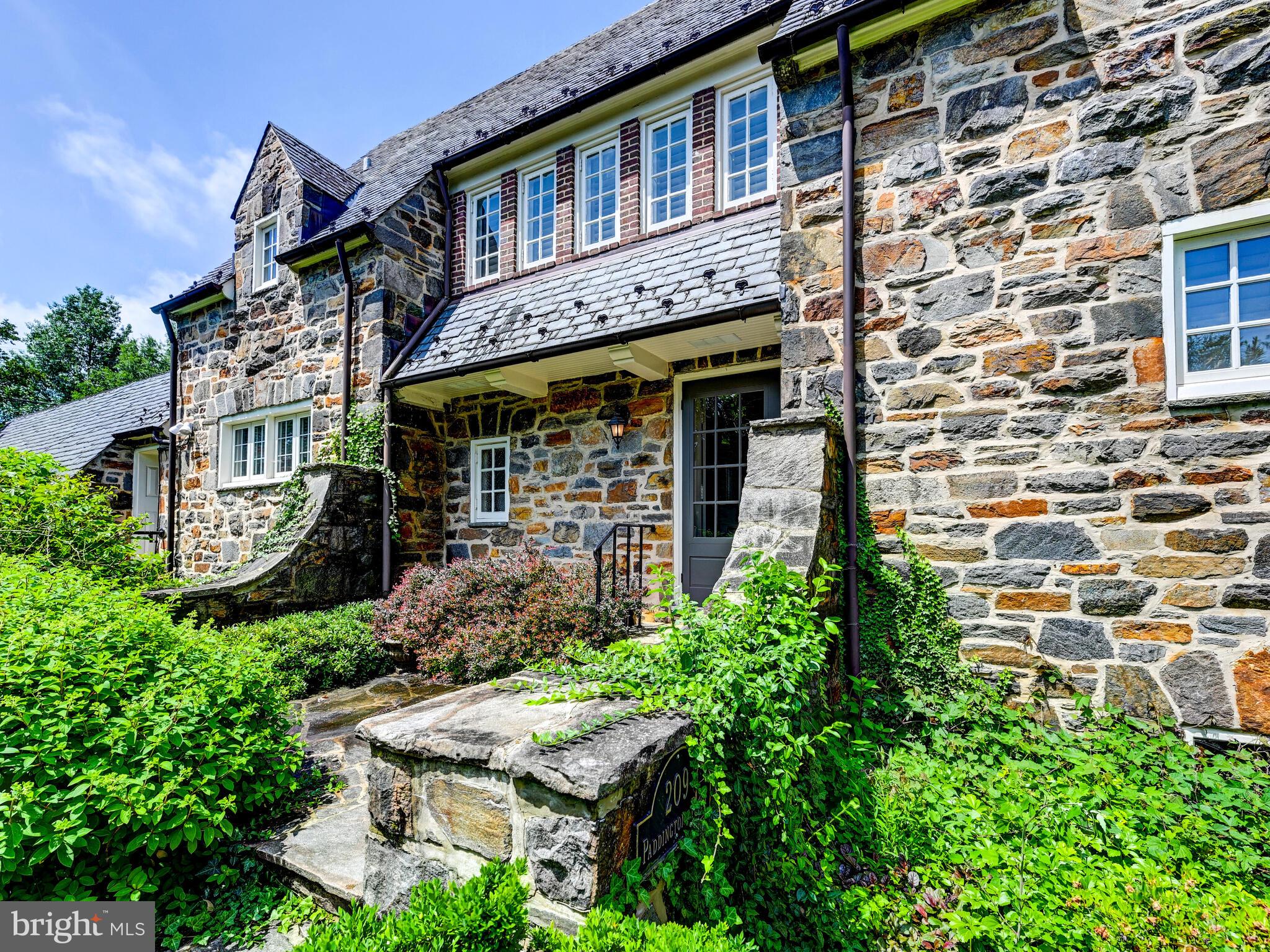 Nestled on one of Homeland's most coveted streets, this 1928 stone Palmer & Lamdin jewel masterfully blends architectural distinction with thoughtful modern updates. From the moment you ascend the stone entry terrace, framed by blooming gardens, you're embraced by timeless charm and a sense of place.
Lovingly maintained, the home offers enduring elegance and a lifestyle designed for both comfort and grace.
The main level features a well-appointed kitchen with stainless steel appliances and granite countertops, seamlessly uniting form and function. Just steps away, a spacious pantry and mudroom add convenience and practical storage. The dramatic 27' x 16' living room captivates with its soaring 14' cathedral ceiling, original wood floors, and a stunning wall of windows and doors that bathe the space in light. French doors from both the living room and sunlit dining room open to an extraordinary fieldstone patio, an ideal setting for seamless indoor-outdoor entertaining. The main level also offers a private primary suite, enhanced by a beautifully renovated en suite bath (2019), designed with comfort and accessibility in mind.
Upstairs, a cozy sitting area with a second fireplace provides a peaceful retreat, along with two additional bedrooms-each with its own private bath. The third level features a versatile fourth bedroom or home office, offering flexibility to suit your needs.
The pristine lower level offers ample storage and potential for future finished space. Recent updates include roof and chimney work (2017), water heater(2017), HVAC systems (2023 & 2024), and a new boiler (2023).
Set against a backdrop of lush landscaping and romantic stone architecture, this exceptional residence is both a tribute to classic craftsmanship and a sanctuary for modern living.