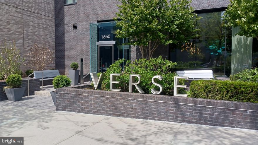 Experience Unparalleled Luxury at The Verse, Unit 1307.  Welcome to a masterfully designed corner residence that epitomizes modern elegance and sophisticated living in Tysons’ vibrant Boro neighborhood. This partially furnished 2-bedroom, 2.5-bath residence spans 1,689 square feet and features over $110,000 in premium upgrades and custom finishes including $100,000 in high-end enhancements and an additional $10,000 in bespoke closet systems. Originally crafted as the builder’s model home, this residence delivers a seamless blend of comfort, style, and functionality, with breathtaking views of the mountains and skyline. | A Sophisticated Sanctuary: The moment you step into Unit 1307, you’re welcomed into an open-concept layout framed by wide-plank wood floors and floor-to-ceiling windows that flood the space with natural light. The expansive private balcony invites you to relax or entertain with stunning panoramic views, while the chef-caliber kitchen sets the stage for culinary artistry. The kitchen, custom-designed by Cecconi Simone, boasts: Full-height Italian cabinetry with integrated storage; Composite stone countertops with a dramatic waterfall edge; Bosch appliances, including a concealed refrigerator, dishwasher, and microwave; A wine fridge, five-burner gas cooktop, and wall-mounted oven; and Oversized Island with seating, storage, and USB ports. The primary suite is a private retreat, offering custom-built dual walk-in closets with mirrored doors and a spa-inspired bath featuring porcelain Calacatta marbleized tile, a frameless glass shower with an integrated bench, and a custom Italian vanity with built-in linen cabinetry and warm LED edge lighting designed for makeup application and nighttime comfort. The secondary bedroom is equally luxurious, with an ensuite bath, custom closets, and abundant natural light. Additional conveniences include a stylish powder room, a dedicated laundry room with a stacked washer and dryer, two private garage parking spaces, and a premium storage locker, #30, on the third floor. | Luxe Amenities That Elevate Everyday Living: The Verse offers an array of resort-style amenities designed to complement your lifestyle, whether you’re seeking tranquility or vibrant social spaces. Key amenities include: Stunning Lobby providing an inviting oasis with warm wood and stone finishes, plush fireside seating, and a 24/7 concierge team ready to serve you; Grand Entertainment Lounge with soaring windows, flexible spaces for private events, a 14-foot glass-top island, and an outdoor kitchen featuring Wolf gas grills; One-Acre Skypark offering a lush outdoor retreat with communal dining areas, fire pits, a badminton lawn, and a covered kitchen with bar seating; High-Performance Fitness Studio fully equipped with cardio and weightlifting machines, a yoga studio with programmed workouts, and an outdoor Zen terrace;  and an Outdoor Pool for relaxing poolside with chaise lounges and panoramic views. Additional features include a pet spa, a guest suite with hotel-like amenities, secure bike storage with a repair station, and private resident storage units. The secure resident-only garage offers EV charging stations and preferred parking for fuel-efficient vehicles. | A Curated Lifestyle at The Boro: The Verse is located in the heart of The Boro, Tysons’ premier mixed-use neighborhood. Steps away, you’ll find upscale dining options, including North Italia, Circa, and Flower Child, the flagship Whole Foods Market and ShowPlace Icon Theatre, and pedestrian-friendly streetscapes. With easy access to the Silver Line Metro via Greensboro Station and major roadways, The Verse provides unmatched connectivity while offering a serene refuge from the hustle and bustle. | Your Luxury Living Awaits: Enjoy this rare opportunity to rent a meticulously curated residence where the only thing missing is you.