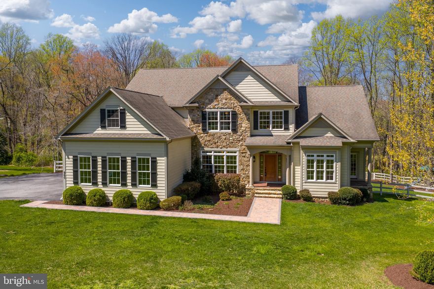 Set on over five acres of beautifully landscaped, tree-lined grounds with tranquil pond views, this exceptional property offers a rare blend of privacy, natural beauty, and refined living in the heart of Western Howard County. Built in 2010, the home presents a thoughtfully designed, expansive layout ideal for both everyday comfort and seamless entertaining.  A welcoming front porch and side-entry three-car attached garage lead into a functional mudroom complete with beadboard accents, a utility sink, and built-in bench seating. The foyer is elegantly flanked by formal living and dining rooms, showcasing rich hardwood flooring, soaring and tray ceilings with cove lighting, crown molding, and an abundance of natural light.  At the heart of the home, the gourmet kitchen is beautifully appointed with warm finishes, a center island with breakfast bar, 42” soft-close cabinetry, a spacious pantry, stainless steel appliances, granite countertops, a rustic stone backsplash, and a convenient pot filler. The kitchen opens seamlessly to a light-filled morning room and an impressive two-story great room featuring coffered ceilings, custom built-ins, plush carpeting, and a gas fireplace with a stone surround.  The adjacent breakfast area boasts a vaulted ceiling, skylights, ceramic tile flooring, and access to exceptional outdoor living spaces, including an open deck, a fenced yard with pristine landscaping, and a screened-in porch with its own wood-burning fireplace, perfect for year-round enjoyment.  The main-level primary suite serves as a private retreat, offering plush carpeting, a walk-in closet, a double tray ceiling with cove lighting, and direct access to a secluded porch. The luxurious en-suite bath features a soaking tub, walk-in shower, and dual vanities. A powder room completes the main level.  Upstairs, a wrought-iron-accented staircase leads to a well-appointed upper level with a private bedroom suite and updated en-suite bath, two additional bedrooms (including one with an expansive bonus space), a hall bath, and a versatile loft ideal for a lounge, media, or game area.  The fully finished walkout lower level expands the home’s versatility with a spacious recreation area, modern flooring, a kitchenette, home gym, bonus room or potential bedroom, full bath, and abundant natural light.  A standout feature is the custom detached garage, offering three oversized bays ideal for RVs, ATVs, or car enthusiasts, along with a powder room and an unfinished upper level ready to be transformed into a home office or studio apartment.  Surrounded by nature yet conveniently located near MD-32, I-70, shopping, dining, Western Regional Park, Circle D, Cattail Creek Country Club, and top-rated schools, this extraordinary property offers the perfect balance of seclusion and accessibility. Designed for a lifestyle of comfort, functionality, and connection, this is a rare opportunity you won’t want to miss.