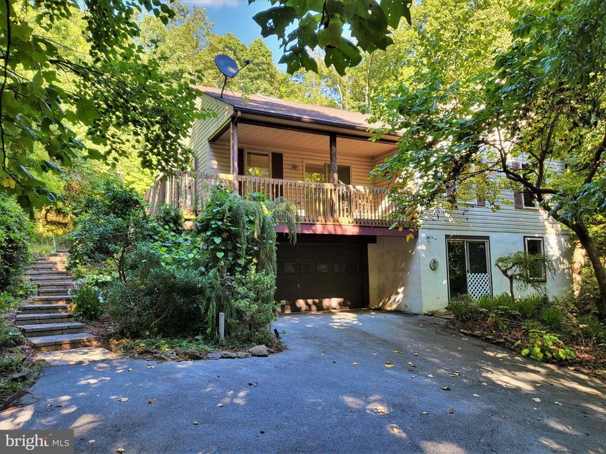 Cozy rancher nestled in the forested community of Potomac Woodlands.  The home is situated on 3 wooded acres with access to a stream.  Just steps from the property you'll find community recreational space and private trails that lead to the C&O Canal Towpath and Potomac River.  The exterior of the home features a wrap-around deck, which is fully covered on the front portion of the home.  Enjoying the views and wildlife on your property is convenient thanks to this covered outdoor space.  The rear yard offers a concrete patio, perfect for your outdoor grill and patio furniture.
The home is part of an estate and is being sold as-is.  The home does need work to include new flooring throughout.  The previous owner had cats that did damage to carpets, subflooring and sections of baseboard trim, which will need addressed.  All carpeting has been removed from the home at this time. 
The main level offers an open floor plan with cathedral ceilings and sky lights.  Situated in a heavily forested lot, the sky lights allow a lot of natural sunlight you'd otherwise not get through the windows.  The living room offers sliding glass doors the front covered deck and is open to the kitchen and dining area.  The dining area offers sliding glass doors to the rear patio and yard.  The kitchen features oak cabinets, a pantry, all appliances (as-is) and vinyl floors. 
Back the hall you'll find 3 bedrooms and 2 baths on the main level.  The primary bedroom features a spacious walk-in closet and private bath complete with tub/shower combo.
On the lower level you'll find the homes utility room, a front loading garage and a large open room that offers full size windows and sliding glass doors to the front yard.  This room could easily be finished for additional living space and would make for a perfect rec room.