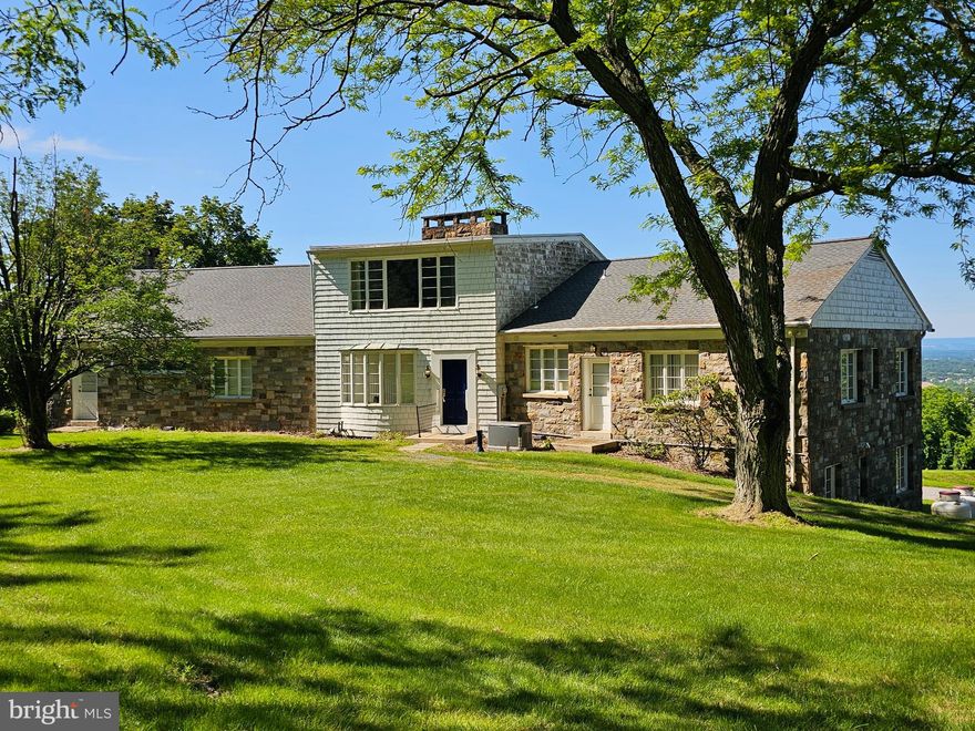 Breathtaking fall foliage vistas sweep across the Valley, to the Blue Mountain.  Nestled into the South Mountain hillside, this 4100+ sq ft home offers a unique opportunity for those seeking tranquility and privacy.  Built with character, this unique 1950's home awaits your personal touch.  While the home needs work, envision the possibilities to transform it into your dream oasis.  (5) Stunning stone fireplaces add character to each space, and hardwood flooring throughout the main level.  Main level features large windows creating a seamless connection to the outstanding views, and hardwood flooring on the main level.  Imagine waking up to panoramic views of the Lehigh Valley where each season paints a picture.  Flexible living space in the lower-level 1 bedroom apartment with a private entrance and living room, perfect for extended family, guests, or caregiver. This property strikes the perfect balance between seclusion and accessibility.  Convenient to LVHC, shopping, major highways, and PA Turnpike Ext.  Savvy buyers will recognize the value of this property as it invites you to make it your own.