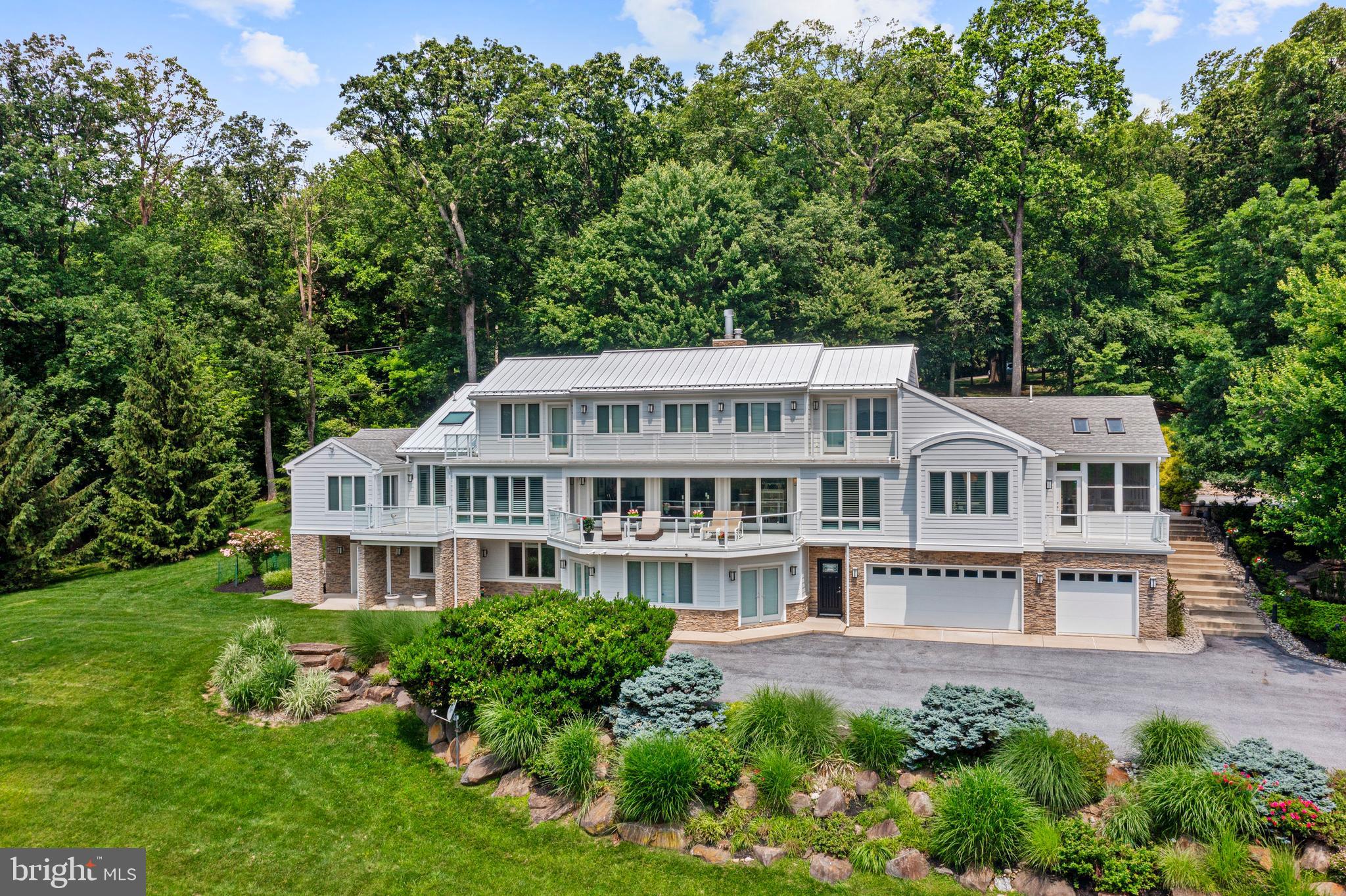 Nestled atop the serene and picturesque landscape of Valley Forge Mountain, this architectural masterpiece awaits. Occupying five bucolic,private acres, this rare gem offers an unparalleled living experience within the esteemed Tredyffrin/Easttown School District. With 6,635 square feet of completely renovated, sensational living space, this residence is a testament to exquisite craftsmanship and sophisticated design.
Upon entry, a grand foyer welcomes you into a breathtaking great room, distinguished by its soaring 22-foot ceilings, custom Marble floors, and an oversized marble fireplace. An abundance of windows throughout, and French patio doors bathe the space in spectacular natural light, offering panoramic vistas, stunning views of the valley and the surrounding natural beauty. Step through these doors onto a gorgeous deck that overlooks a spectacular backyard oasis, a perfect setting for tranquil relaxation or grand-scale entertaining.
The art of entertaining is perfected in the oversized, beautiful dining room, which flows seamlessly into the heart of the home: the stunning gourmet kitchen. Prepare to be captivated by this extraordinary, sun-drenched culinary haven. Featuring high ceilings with two skylights and two oversized Carrera marble islands, this state-of-the-art kitchen is a chef's dream. Top-of-the-line appliances include a 6-burner Wolf dual range with griddle, three Wolf ovens, a warming drawer, a built-in Sub-Zero refrigerator, an additional under-counter Sub-Zero refrigerator and freezer, a wine refrigerator and icemaker in the bar area, and a walk-in pantry.
Adjacent to the kitchen, an enclosed sun porch, or three-season room, offers a tranquil retreat with expansive views through its oversized windows. For more casual gatherings, a sensational family/theatre room off the kitchen boasts two-level seating and custom built-ins.
The magnificent first-floor primary suite is a sanctuary of its own, featuring high ceilings, an enormous walk-in closet, and an additional large sitting room with a gorgeous private deck. The convenience of a spacious laundry room with custom built-in cabinetry is also found on this level. The en-suite master bathroom is a study in luxury, with stunning Travertine floors, an oversized double shower , a wonderful Jacuzzi tub, a gorgeous double sink vanity, custom cabinetry, linen closets, ample storage, and his-and-hers water closets.
The second floor reveals a charming balcony overlook and a south-facing deck that spans the entire length of the floor, offering truly panoramic views. This level hosts a second magnificent master suite, complete with a large walk-in closet and a gorgeous master bath. An additional beautiful office or bedroom with deck access completes this floor.
The beautifully designed lower level extends the living space with three additional large bedrooms and a new, gorgeous bathroom. This level also features a separate laundry room, a workout room, wine storage, and a sauna. An enormous family room with a built-in wet bar and custom bookcases provides another fantastic entertaining space. From here, an additional oversized office with two sets of French doors opens out to the beautiful backyard.
This exceptional property also includes a six-plus car garage, as well as an additional storage garage for lawn maintenance equipment. With its stunning landscapes and flourishing gardens, this home is truly a sensational place to call home and a perfect venue for creating lasting memories.
