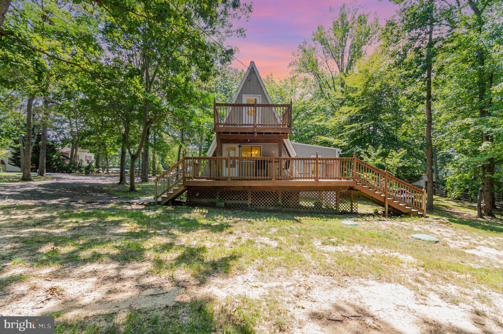 This unique 3-bedroom, 2-bathroom A-frame home in Lusby sits beautifully on a spacious corner lot, offering character, charm, and plenty of room to relax and entertain. Step inside to find gorgeous hardwood floors and cozy shiplap walls throughout the main level, where the open-concept eat-in kitchen flows effortlessly into the inviting living space. The main-level primary suite is a true retreat, complete with its own en-suite bath and durable LVP flooring. A spiral staircase leads to two generously sized bedrooms upstairs, each filled with natural light. Outdoor living is a dream with four separate decks—two in the front and two in the back that were all redone—perfect for sipping your morning coffee or hosting friends for summer barbecues. The fully fenced, level backyard offers ample space for your favorite people and pets to enjoy. Ideally located just minutes from shopping, restaurants, Solomons Island, and the Patuxent River Naval Air Station, this one-of-a-kind home blends comfort, style, and convenience.