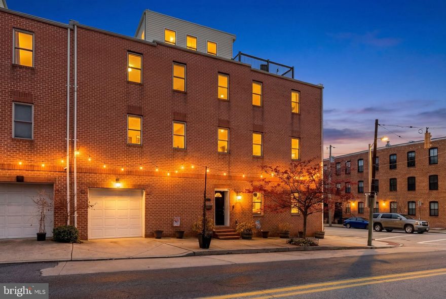 Stunning 50' wide brick end of row townhome offering five floors of luxury living located in the heart of  Canton! This 3BR/3Full-2HalfBA with an attached garage boasts tons of upgrades such as ethernet throughout, built-in speakers in every room, recessed lighting, gleaming hardwood floors on all floors, tons of natural light, and high end finishes.  Enter into the main floor boasting an open floor plan featuring an extraordinary kitchen and dining room, a powder room, and access to the garage which offers a 7000lb rated garage lift for parking two cars inside. The gourmet style kitchen boasts plenty of custom cabinets finished with crown moldings, stainless steel appliances including a slide-in gas range with a stainless range hood, gorgeous granite countertops with a glass subway tile backsplash, an island with a curved end hosting a stainless sink with a raised breakfast bar offering breakfast seating for three or more, and pendant lights. The custom cabinets continue into the dining room offering additional storage including two pantry cabinets, a desk area with storage above, and a cozy bench under a window, an ideal space for sipping your morning coffee. Start by taking the open staircase to the lower level which offers a spacious recreation room, a half bath, and room for storage.  Just above the main floor is an oversized living room featuring a stately gas burning fireplace, a full bath, a laundry closet, and the first of three bedrooms which offers two closets. On the third floor you will find a sizable secondary bedroom, a full bath, and a grand sized primary suite. The large primary bedroom has not one, but two walk-in closets both with custom built-in closet organizers, a stunning en-suite which features heated WiFi programmable flooring, a jetted soaking tub, a double sink vanity, a large walk-in shower with a built-in bench, and a linen closet. One more space to explore, the rooftop entertainment space which offers a wet bar with custom cabinets, granite countertops, a Scotsman wine chiller and ice maker.  From here step outside to the newly replaced rooftop deck which gives you beautiful views of the skyline and room for hosting family and friends. In addition to all this, this home features a new roof with a 20 year warranty and new Trex decking.  This stunning home is perfectly situated just moments from Canton's vibrant dining, shopping, and major commuter routes!