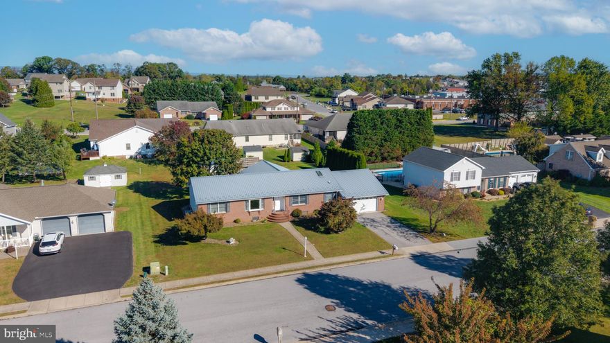 Located in a Town & Country neighborhood of Greencastle at the edge of town, this 3-bedroom, 3-bath home offers 3,184 sq ft of finished living space on a nicely landscaped lot with beautiful Japanese and Norway maple trees and a convenient paved driveway. The home features a newer metal roof with skylight, and a two-zone heat pump system for economical heating and cooling. A large north-facing deck off the morning room overlooks the backyard and connects directly to an above-ground pool, creating a versatile outdoor recreation area. The property also includes a patio with grill area, a fire pit area with seating, and a storage shed with a metal roof for added lifespan.
The main level features an open layout between the kitchen and morning room, a spacious dining area, living room, three bedrooms, and two full baths. The attached two-car garage has a secondary stairway leading to the lower level, providing a separate entrance option for flexible & possible multi-gen. living arrangements.
The lower level includes a kitchen, bath, and open area, well suited for an in-law suite, extended living space, or future customization.
The property is situated just a few minutes from I-81 and the Maryland line, offering excellent regional connectivity. Grocery stores are approximately 1 mile away, and Hagerstown, MD, is a 15-minute drive. Dining options including Mikie’s Restaurant and Tony’s Pizza are just a short distance away.
The interior offers a solid functional layout with opportunity for cosmetic updates such as fresh paint and finishing touches. This home blends outdoor living features, convenient access to amenities, and flexible interior spaces in a well-located neighborhood.