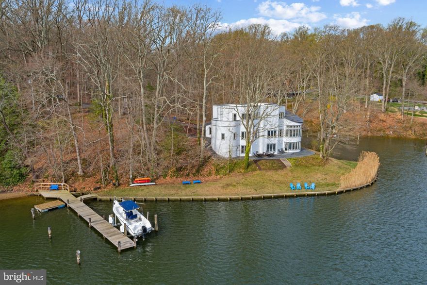 This stunning contemporary three-level home on Mill Creek has been completely renovated from top to bottom, seamlessly blending modern design with breathtaking waterfront views. With 375 feet of shoreline, a private deep water pier (7 ft MLW) with boat lift and a sandy beach, this home offers an unparalleled waterfront lifestyle. The meticulous remodel includes but is not limited to new windows, stunning new flooring, upgraded utility systems and updated kitchen and bathrooms, all of which enhanced both form and function throughout the home. The striking exterior features sleek metal-clad siding, accent metal roofing, and expansive windows that flood the interior with natural light while framing panoramic water views. The main level welcomes you with soaring ceilings in the elegant living room, where a dramatic curved wall of windows and a wood-burning fireplace create a warm yet sophisticated ambiance. The open floor plan flows seamlessly from the dining area into the gourmet kitchen, featuring a peninsula and island—both with seating—alongside a casual dining space perfect for everyday meals. A main-level bedroom with windows overlooking the water and a full bath complete this level. Upstairs is dedicated to the primary suite which offers a true retreat with a spa-like ensuite bath, a private rooftop deck, and an open loft-style space ideal for a home office or sitting area. The lower level is designed for relaxation and versatility, with two additional water-view bedrooms, a full bath, and a spacious family room with a wood-burning fireplace and direct access to the backyard and waterfront. A laundry room, tons of storage and a convenient kitchenette make this level perfect for guests or extended stays. Head down to the water’s edge and set out for a day on the water, perfectly located to take advantage of the Chesapeake Bay's best cruising and fishing areas. Attractive destinations such as the Annapolis Harbor, Baltimore's Inner Harbor, St. Michaels, Oxford, and Solomon's Island are only a short cruise away and just minutes from accessing Rt. 50 and 97 which provides direct access to Baltimore, BWI, Ft. Meade/NSA and Washington, DC., or head over the Bay Bridge to the Eastern Shore for a quick beach vacation.  Welcome Home!