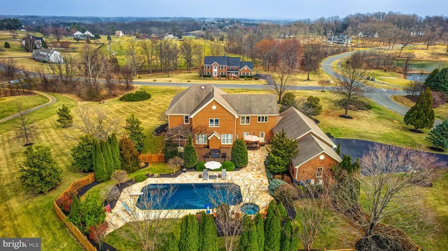 Experience resort-style living in this custom-built, all-brick estate set on nearly 3 acres in the prestigious Stoneleigh Country Club. Boasting over 7,000 sq. ft. of luxurious living space, this home was completely updated in 2020, blending modern amenities with timeless elegance. Enjoy breathtaking golf course and mountain views, a rare 4-car side-load garage, and a private backyard oasis featuring a 22’ x 45’ heated pool and spa with a Travertine deck—perfect for relaxation and summer fun. Designed for both grand entertaining and comfortable family living, this exceptional home offers 5 en-suite bedrooms, 5 full baths, and 3 half baths.

Upon entry, a grand oak staircase and beautiful oak hardwood floors spanning the entire main level, complemented by fresh custom paint, set a tone of timeless sophistication. The formal dining room is ideal for hosting gatherings, while the inviting family room features a cozy fireplace and is perfect for entertaining. A versatile flex space/bonus den offers adaptability, and a spacious home office, adorned with a wall of built-in bookshelves, provides a private and inspiring workspace. The screened-in porch captures picturesque views of the lush landscape, seamlessly blending indoor and outdoor living.

The gourmet eat in kitchen is a chef’s dream, boasting a custom vent hood, Elegant Cream color soft-close cabinetry and travertine backsplash, granite countertops, a large center island, stainless steel appliances, a coffee bar with additional storage, and a farmhouse sink overlooking scenic views. Off the kitchen, the family entrance leads to a charming covered porch, perfect for morning coffee or an evening glass of wine. Additional main-level amenities include a spacious mudroom/laundry room, complete with quartz-topped white cabinetry, a subway tile backsplash, a sink, extra storage, and built-in cubbies, as well as a back staircase providing easy access to the upper level. Two updated half baths, located at each end of the home, feature quartz vanities and designer finishes for added convenience.

The primary suite is a true retreat, offering a sitting area and two walk-in closets. The updated en-suite bath is designed for ultimate relaxation, showcasing a quartz-topped vanity, a standalone soaking tub, and a glass-framed shower. The upper level also includes three additional bedrooms, each with updated en-suite bathrooms for added comfort and privacy.

The fully finished walk-out lower level is an entertainer’s paradise, featuring a spacious recreation room with luxury vinyl plank flooring and a gas fireplace. This level also boasts a full wet bar with granite countertops, a wine cooler, an ice maker, a dishwasher, and a sink. A dedicated game area, complete with a conveying pool table, provides endless fun. A third updated half bath adds convenience, while the fifth bedroom or in-law suite includes a walk-in closet and a private, updated full bath. Direct walk-out access to the backyard enhances the seamless transition between indoor and outdoor living.

Step outside to your private resort-style backyard, where a 22’ x 45’ heated pool and spa with a Travertine deck offers year-round enjoyment. The spa operates independently, ensuring relaxation in every season. An expansive Trex deck, screened-in porch, and patio create the perfect setting for outdoor dining, entertaining, or unwinding in the hot tub under the stars. The mature landscaping surrounding the pool and outdoor spaces provides year-round color, creating a serene and picturesque retreat.

Located within the sought-after Stoneleigh Country Club, this meticulously updated estate offers access to world-class amenities, including a championship golf course, clubhouse, tennis courts, and swimming pool, all set against the backdrop of Loudoun County’s scenic countryside.